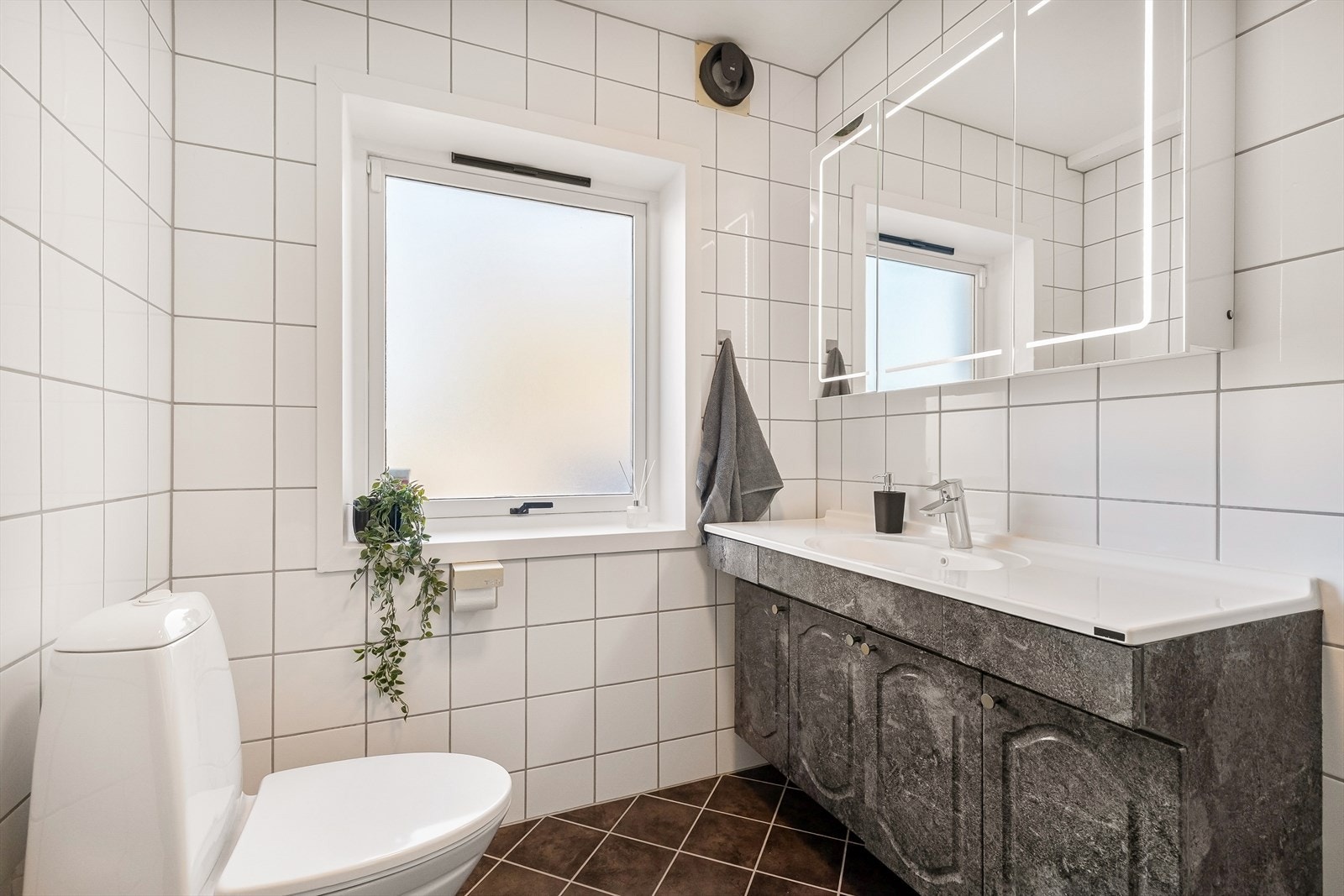 Baderomsinnredning med nedfelt servant og speilskap med integrert belysning. Galleribilde