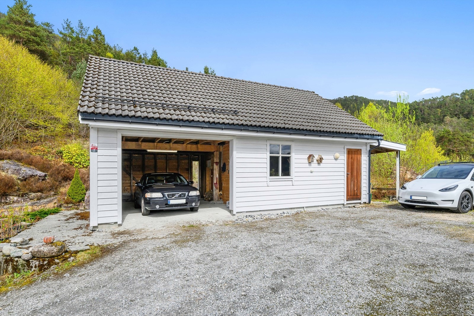 Garasjen fra ca. 2008 har god plass til bil og et tilhørende takoverbygg. Galleribilde
