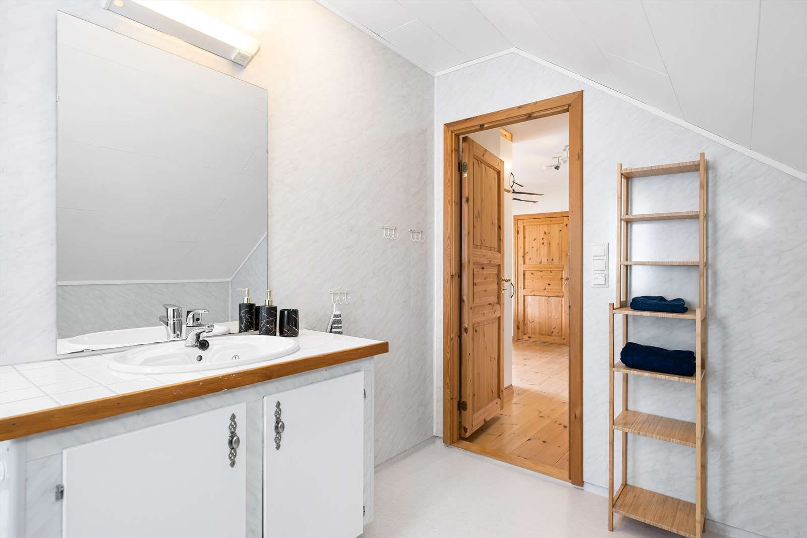 Badet i loftsetasjen har baderomsplater på veggene og servant med underskap. Galleribilde