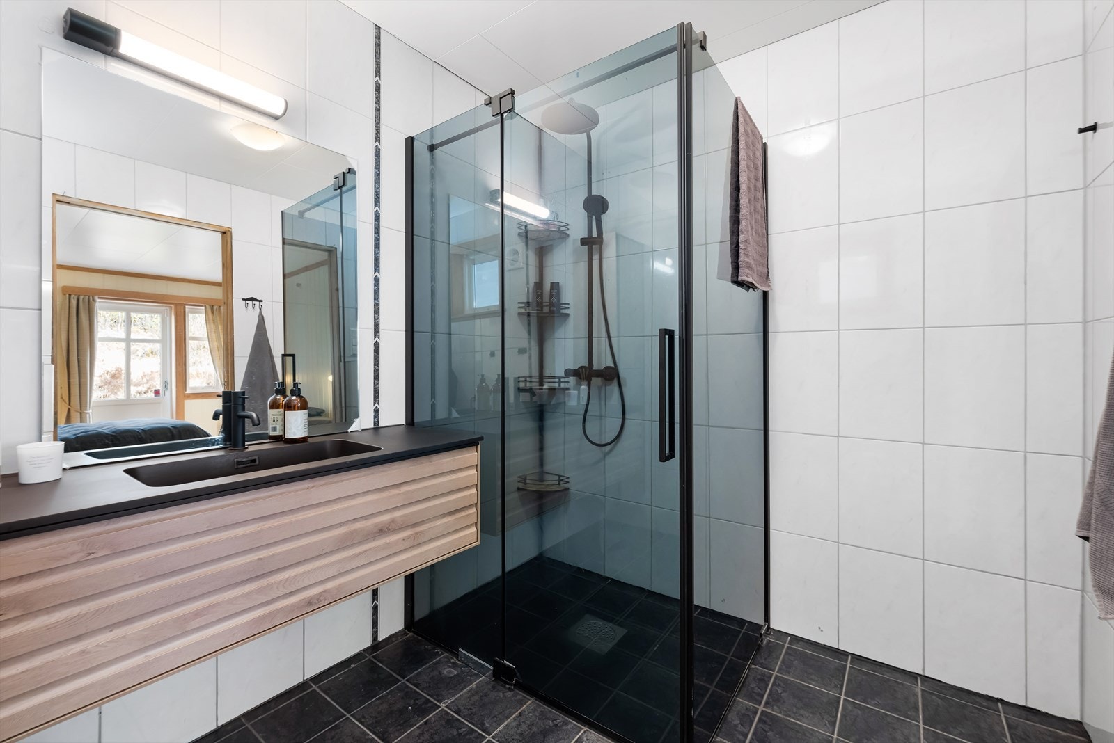 Badet i første etasje har flislagte overflater, dusjhjørne med glassdører og vegghengt toalett. Galleribilde