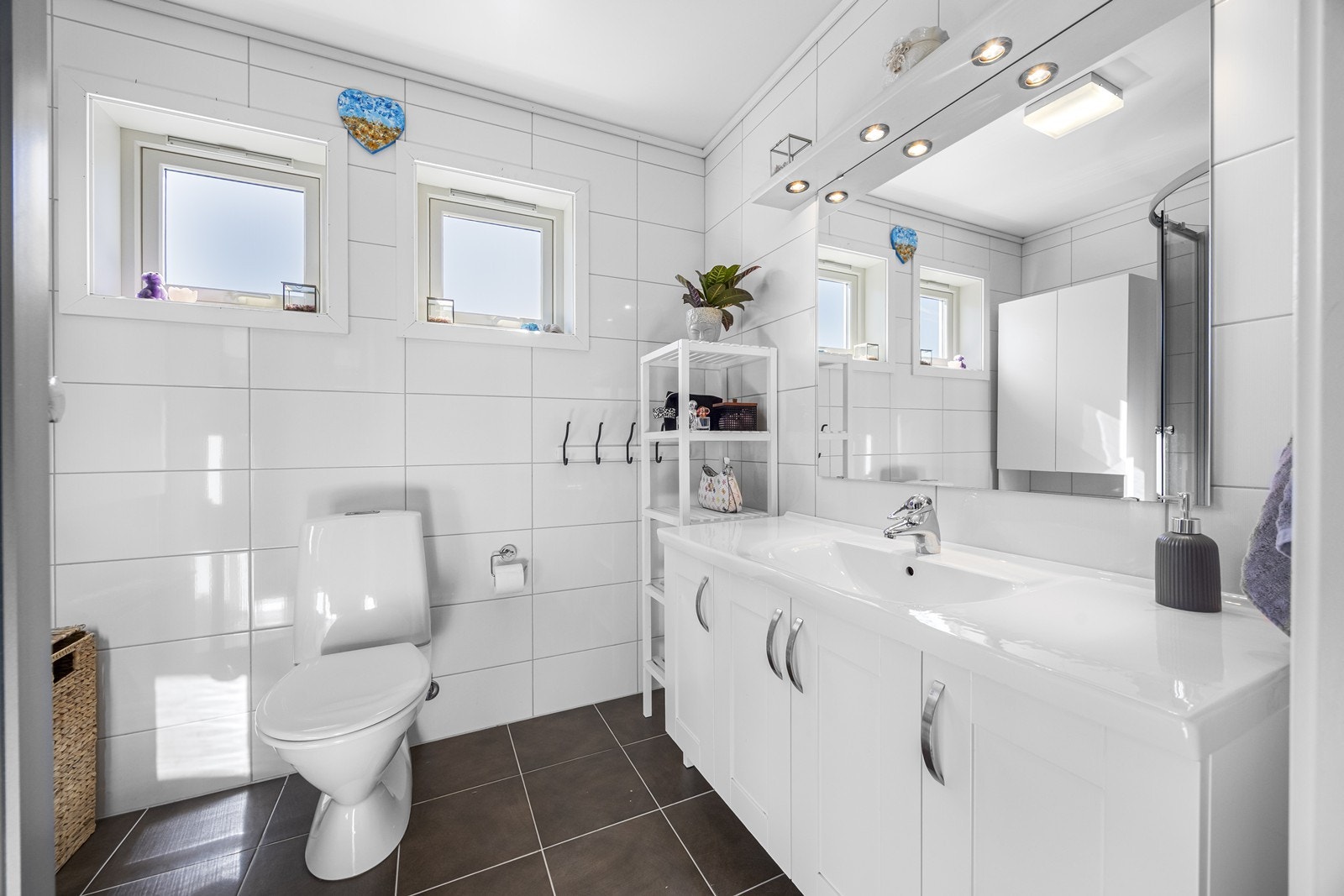 Flislagt bad med varmekabler i gulv. Badet er innredet med wc, baderomsinnredning med god plass til oppbevaring, samt speil med lys. I tillegg dusjkabinett. Galleribilde