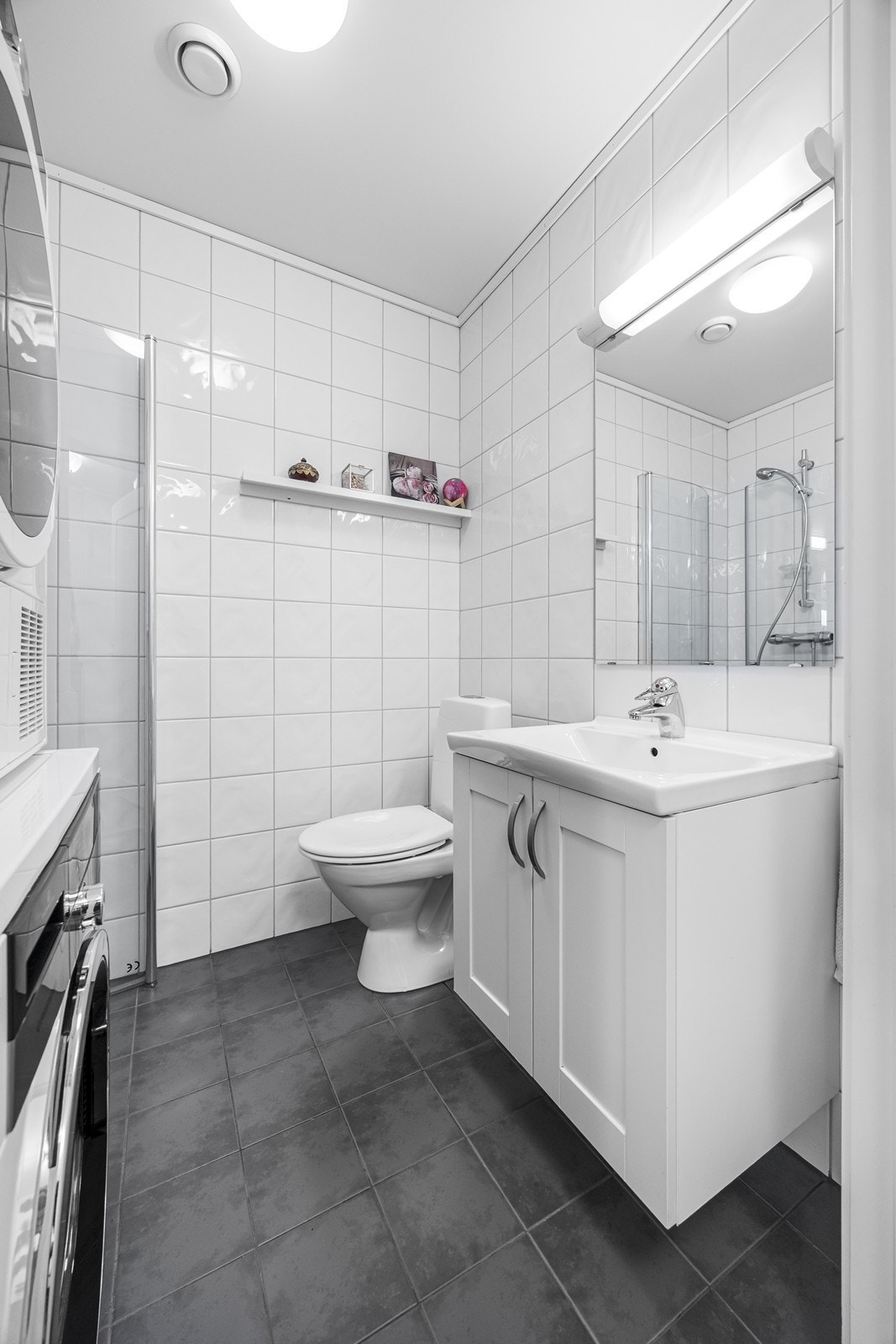 På badet i 1. etasje er det flislagt med varmekabler i gulv. Badet er innredet med dusjnisje med innfellbare dusjdører, wc og innredning med speil. I tillegg opplegg til vaskemaskin og tørketrommel. Galleribilde