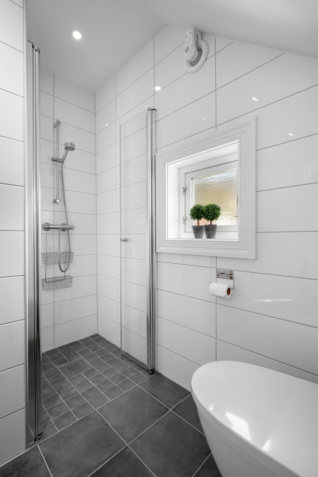 Badet på loftet ble bygget i 2017, med flislagt gulv og dusjhjørne. Galleribilde
