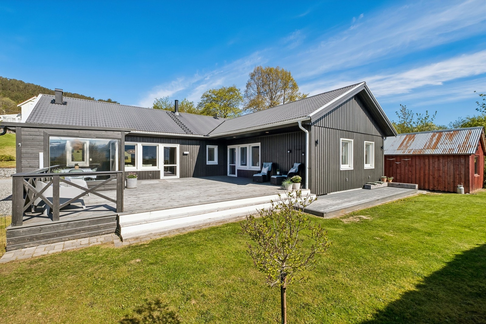 Foran boligen har man et stor terrasse og hage med gode solforhold Galleribilde
