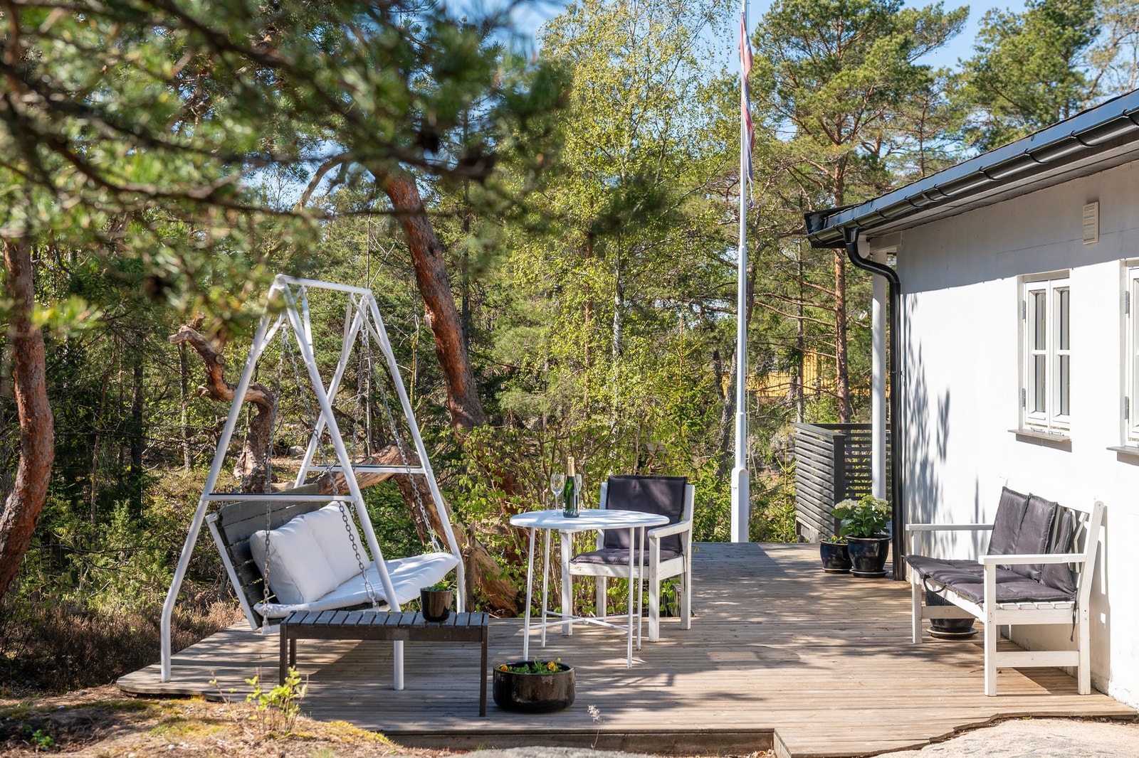 Solrike uteplasser i form av plattinger og veranda som omkranser store deler av hytta Galleribilde