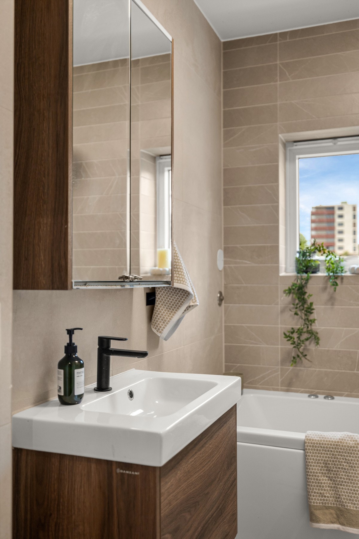 Badet har en moderne og funksjonell utforming med baderomsinnredning bestående av benkeskap med glatte fronter og veggskap med speilfronter over servant. Galleribilde