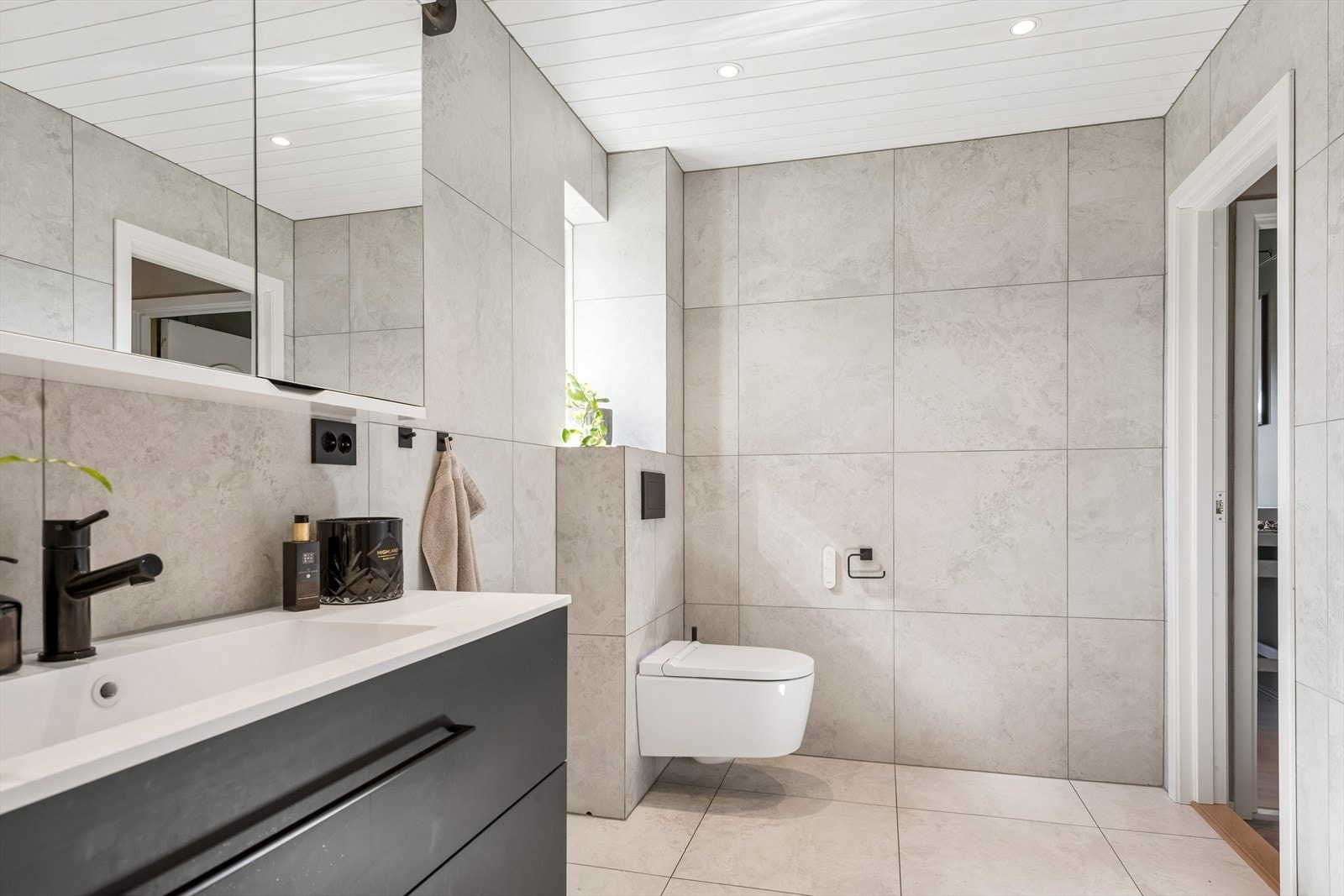 Badet inneholder baderomsinnredning med komposittvask, overskap m/speildører og overlys, høyskap, veggehengt dusjtoalett, dusjhjørne m/2 glassdører og elektrisk håndkletørker. Galleribilde