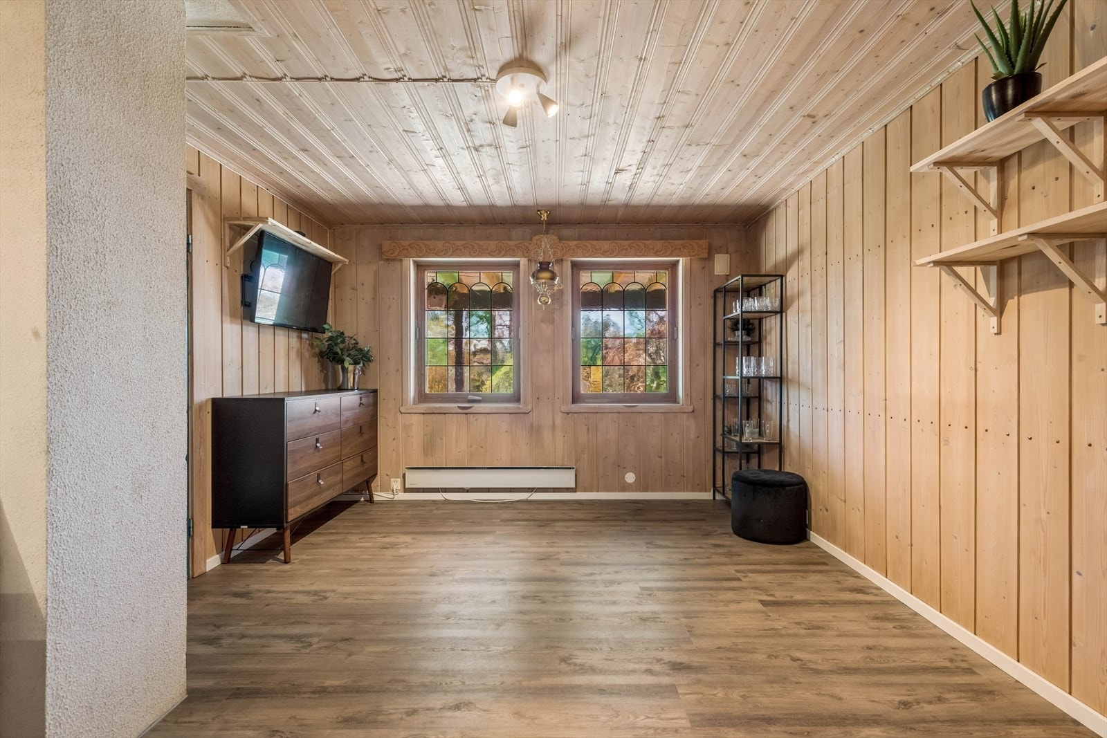 Koselig kjellerstue med panel på vegger og i tak. Det er nyere gulv. Galleribilde