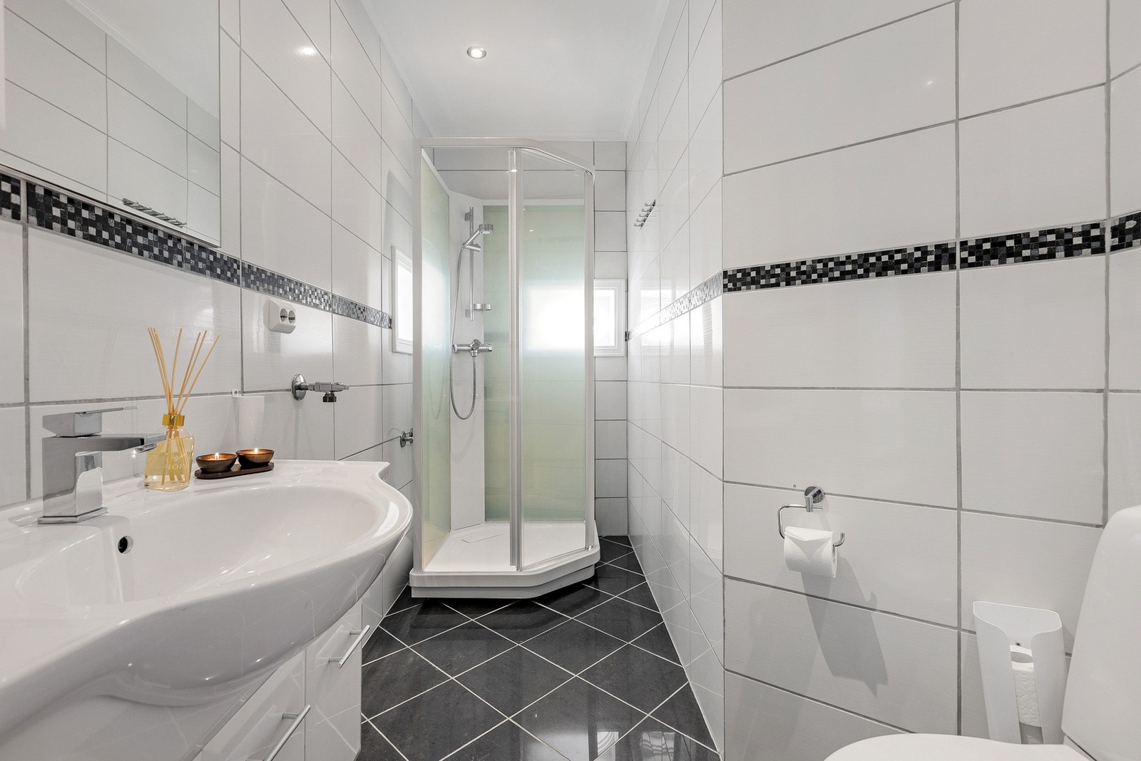 Badet er funksjonelt utformet med flislagte vegger og gulv med elektrisk gulvvarme. Det er også eget toalettrom ved siden av badet. Galleribilde