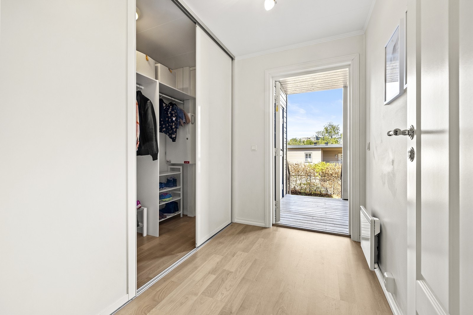 Entré med parkettgulv fra 2017 og en romslig skyvedørsgarderobe for yttertøy og sko. Galleribilde