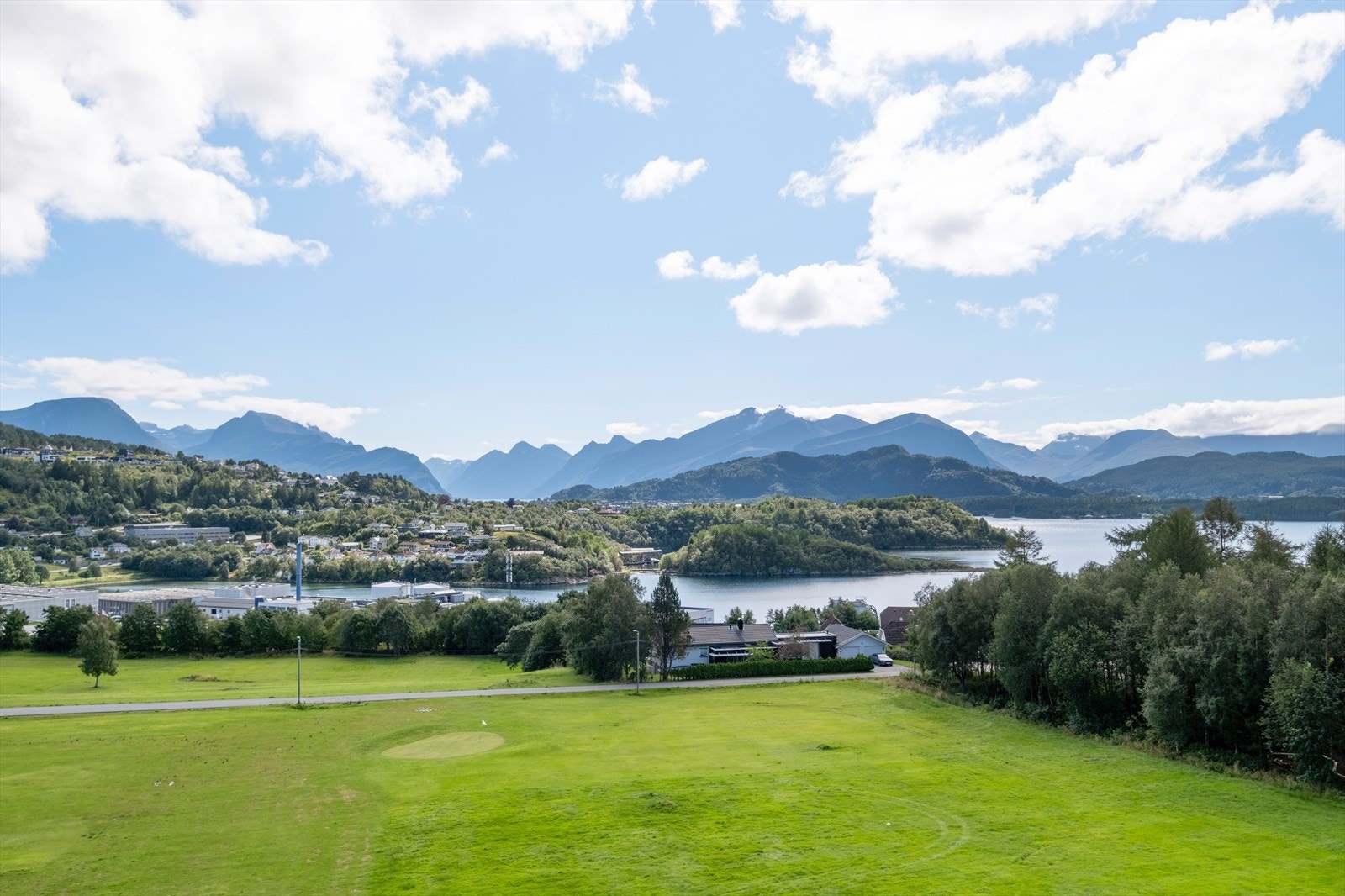 Området har åpne grøntarealer med utsyn mot fjell og vann. Galleribilde