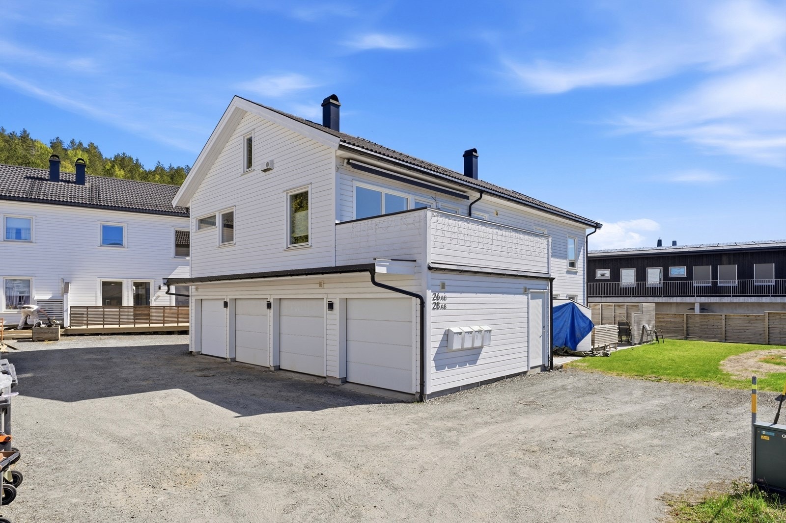 Felles, gruset gårdsplass med gjesteparkering ved siden av garasjene. Galleribilde