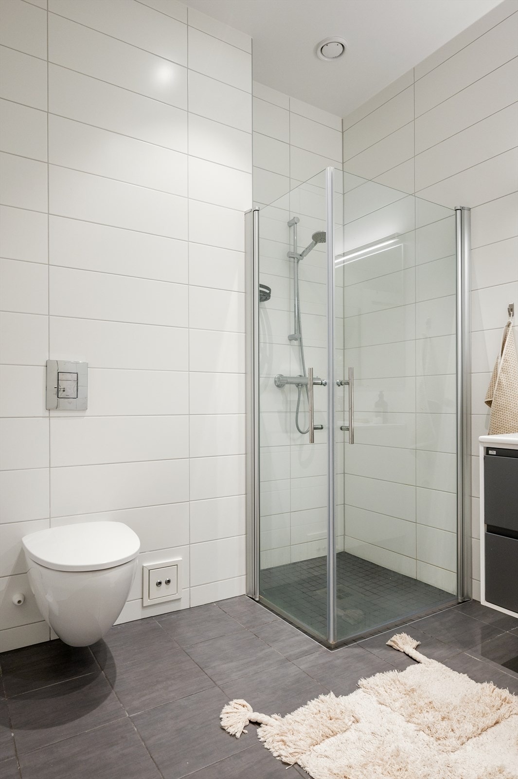 Badet er innredet med vegghengt toalett, servant med tilhørende innredning, speil samt dusjhjørne med svingbare glassdører. Galleribilde