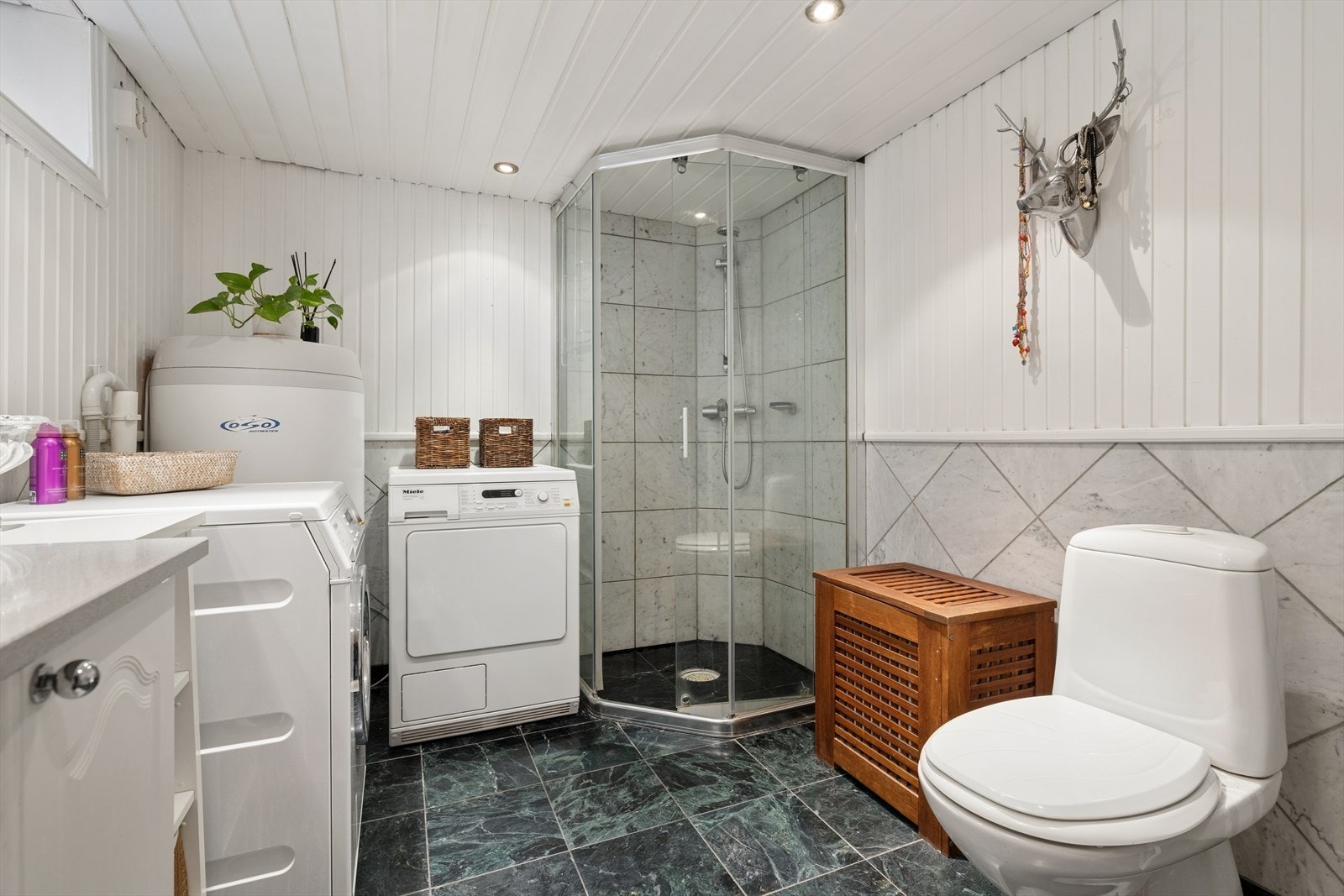 Badet i underetasjen har flislagt gulv med varmekabler, dusjhjørne og opplegg for vaskemaskin. Galleribilde