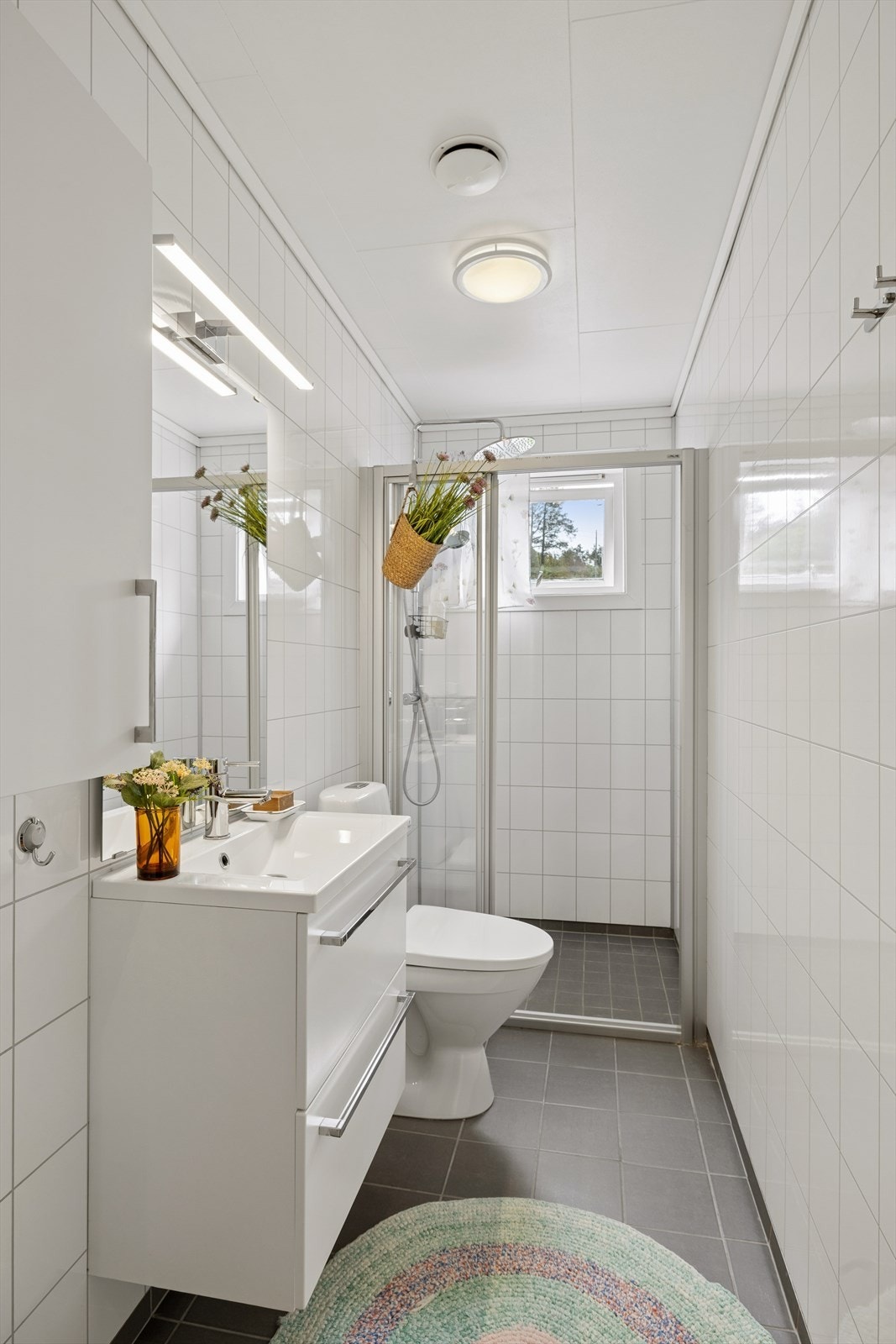 Baderom i 1. etasje. Badet byr på dusjhjørne, toalett og servant med oppbevaring i skuffer. Galleribilde