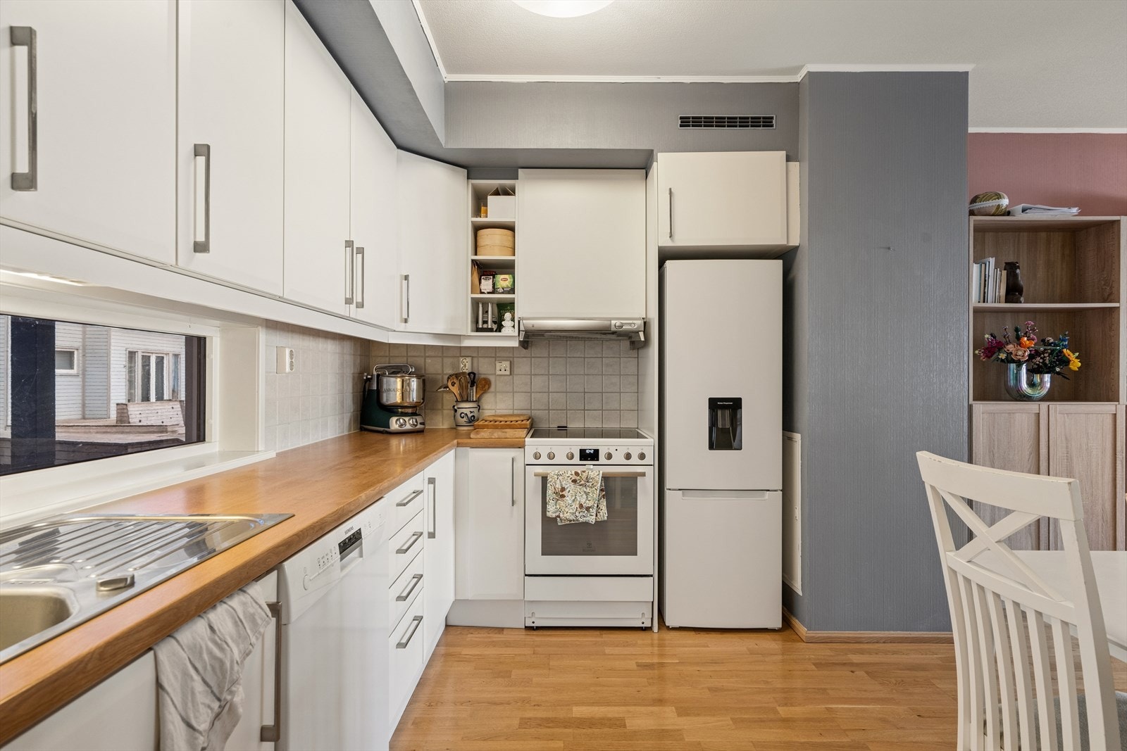 Kjøkkeninnredning med slette fronter, laminert benkeplate og fliser over benken. Galleribilde