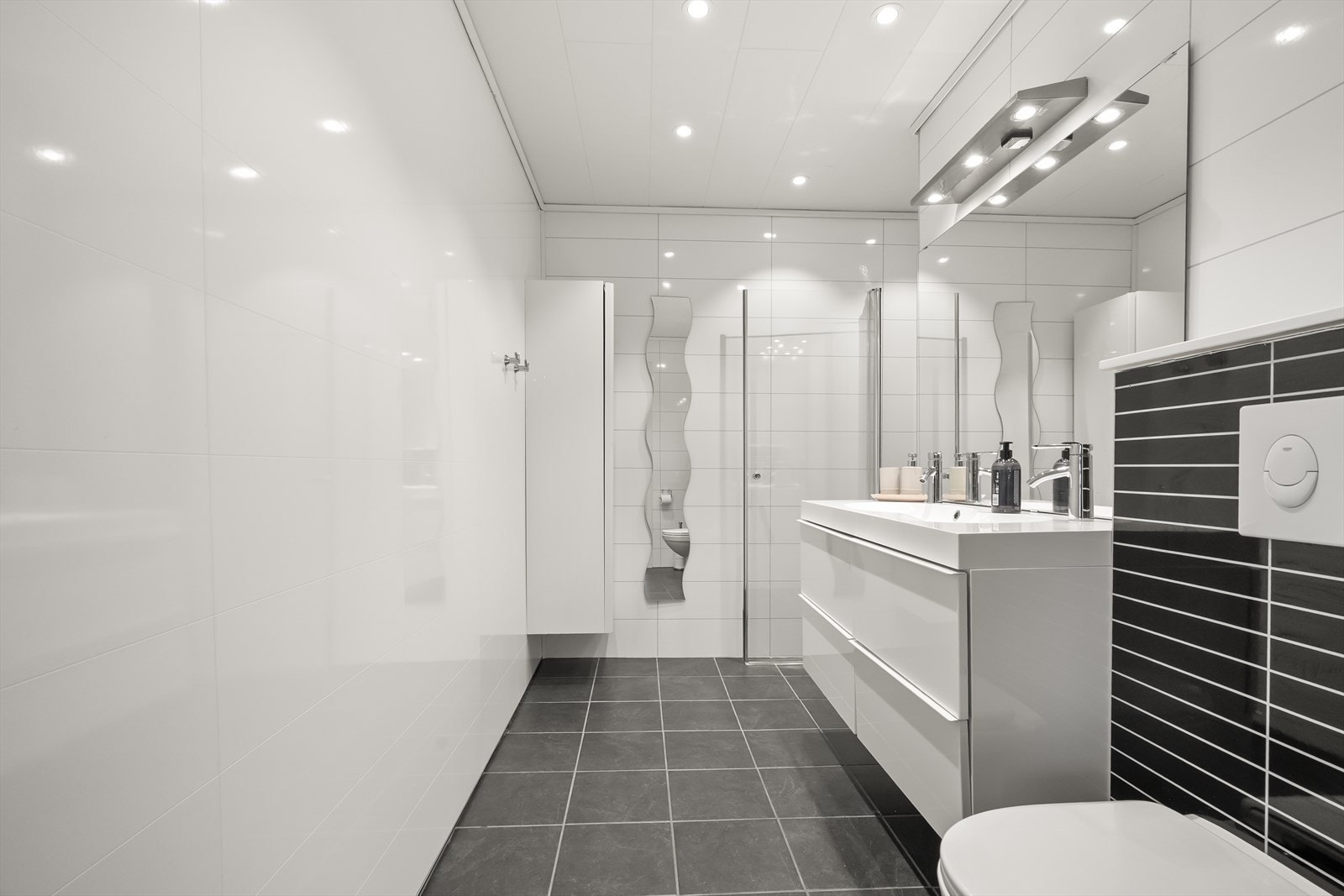 Badet i underetasjen vart oppgradert i 2012. Det har flislagt golv med varmekablar, baderomsplater på veggane og dobbel servant. Galleribilde