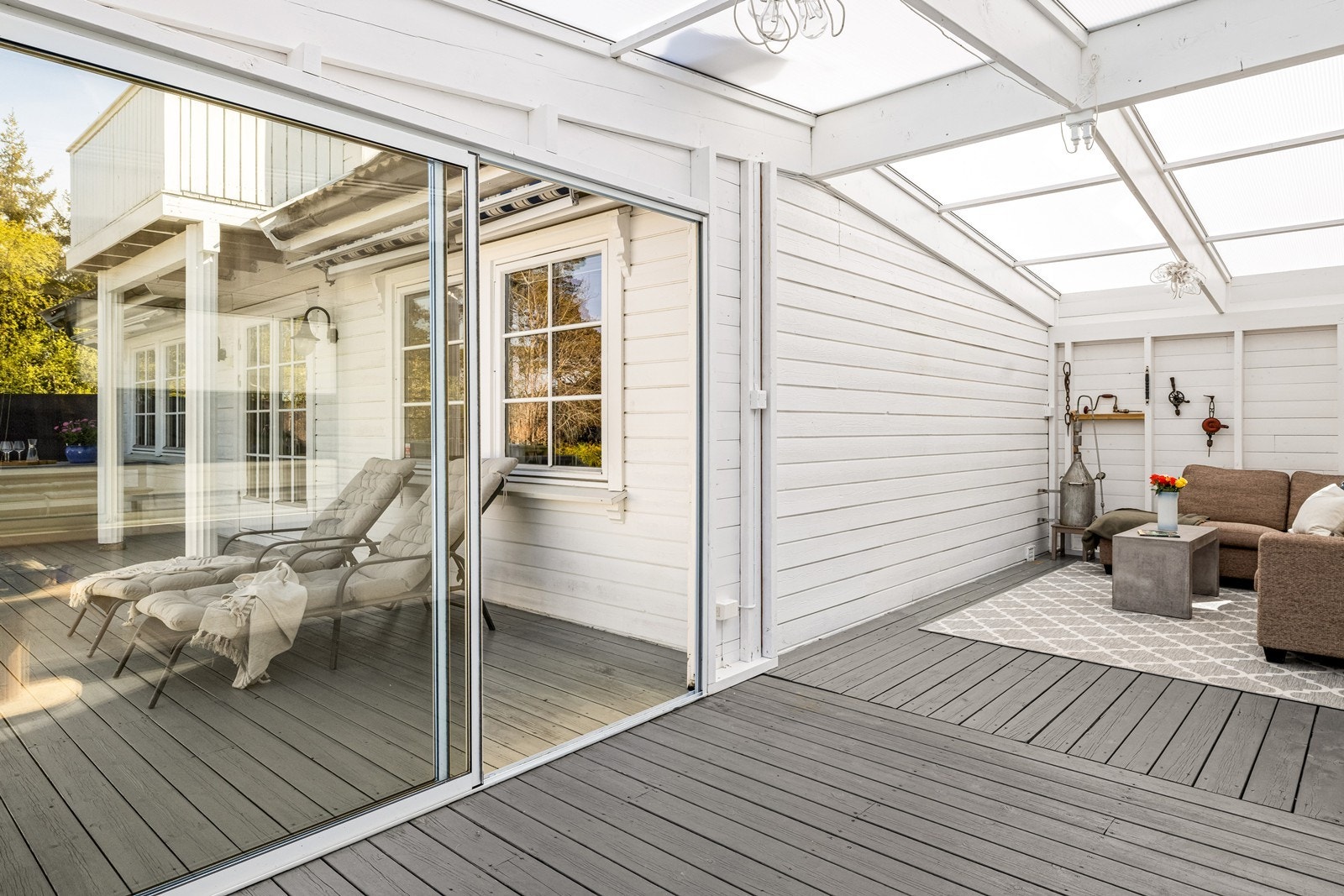 Skyvedører i glass åpner opp mellom terrassen og den innglassede delen. Galleribilde