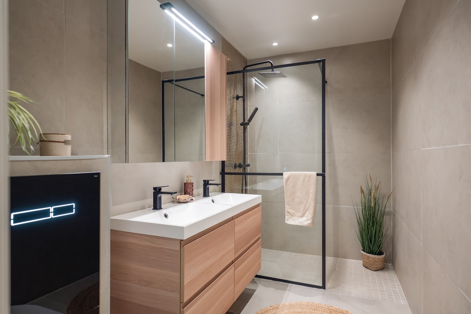 Stilfullt og flislagt bad med behagelige varmekabler i gulvet og downlights i tak, noe som gir et moderne uttrykk. Dusjsonen skiller seg ut med dekorative gullfargede fliser og dusjgarnityr montert på vegg. Galleribilde
