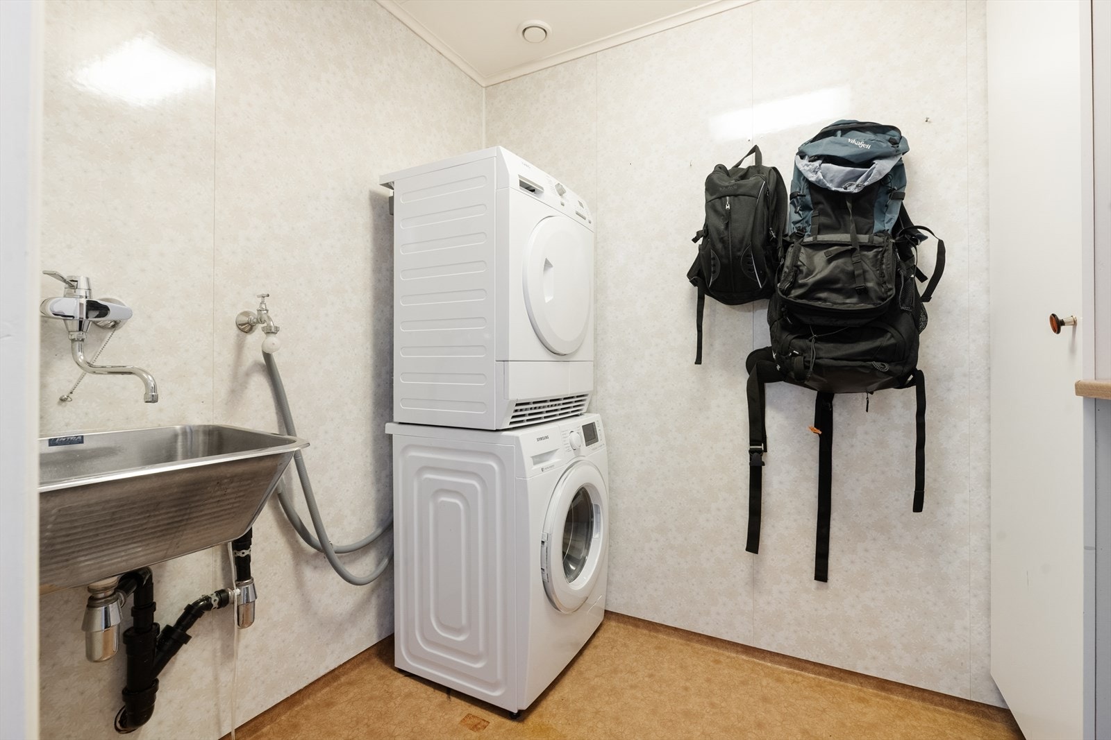 Separat vaskerom med vinylbelegg på gulv med varmekabler, opplegg for vaskemaskin og utslagsvask. Galleribilde