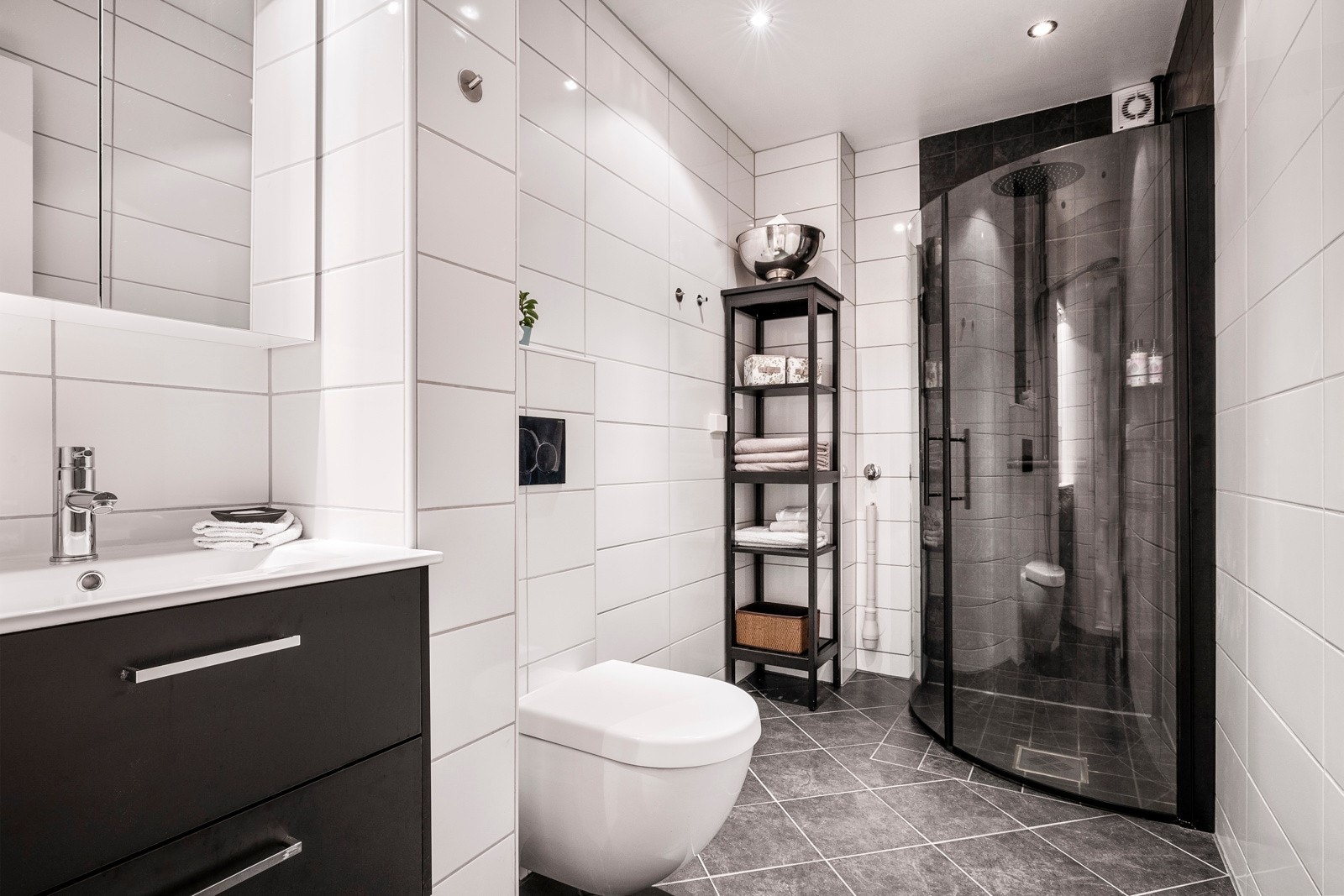 Badet er helfliset i lys utførelse med malte slette takflater. Badet er utstyrt med innfelte downlights, varmekabler i gulv, vegghengt toalett, dusjhjørne, baderomsinnredning med nedfelt servant samt opplegg for vaskemaskin. Galleribilde