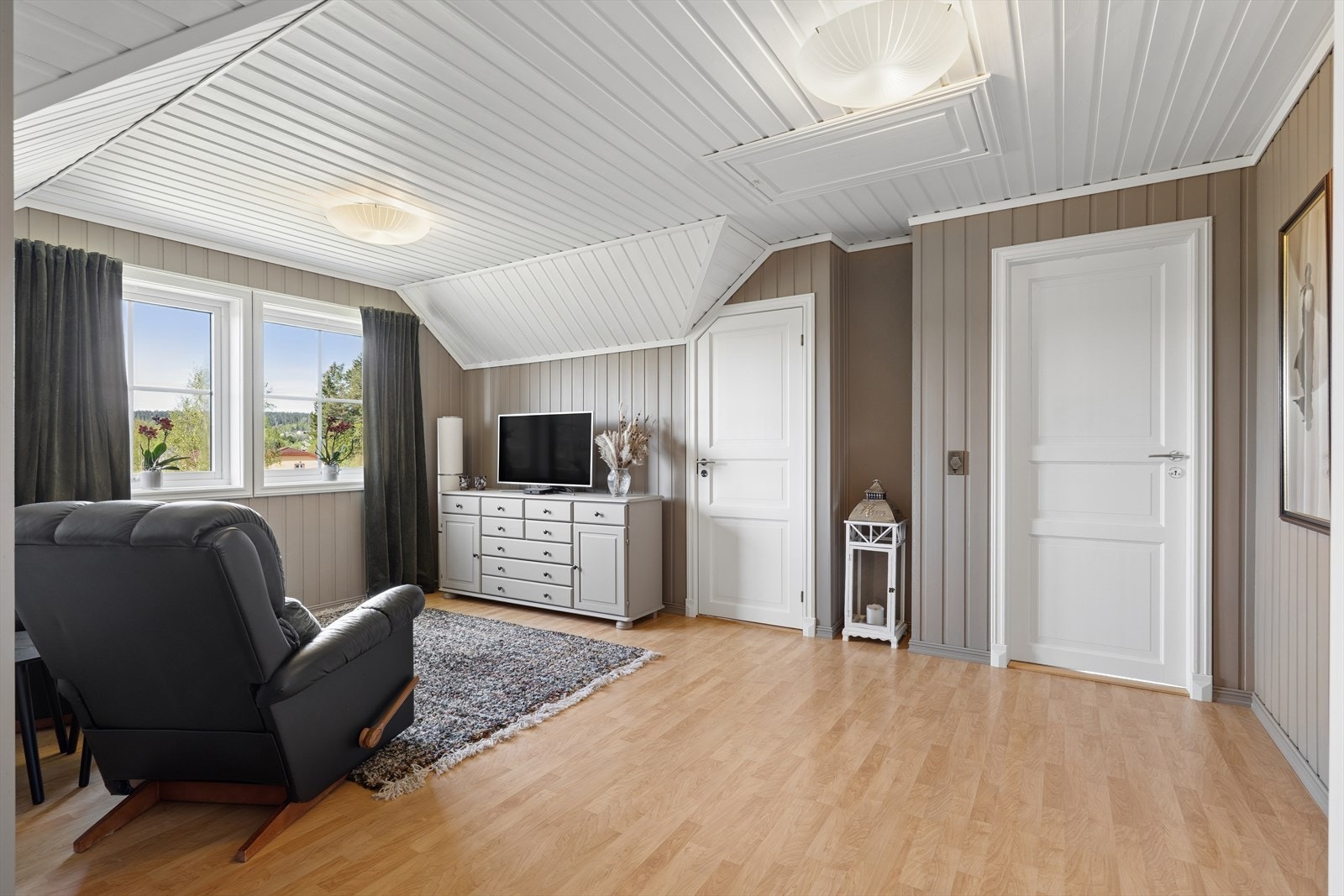 Loftstuen fungerer som et ekstra oppholdsrom og knutepunkt for soverommene i etasjen. Galleribilde
