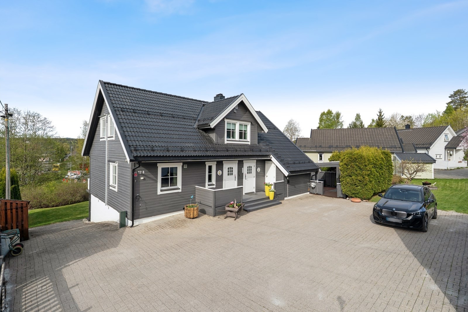Eiendommen har en stor, steinbelagt gårdsplass med elbillader og god plass til parkering. Galleribilde