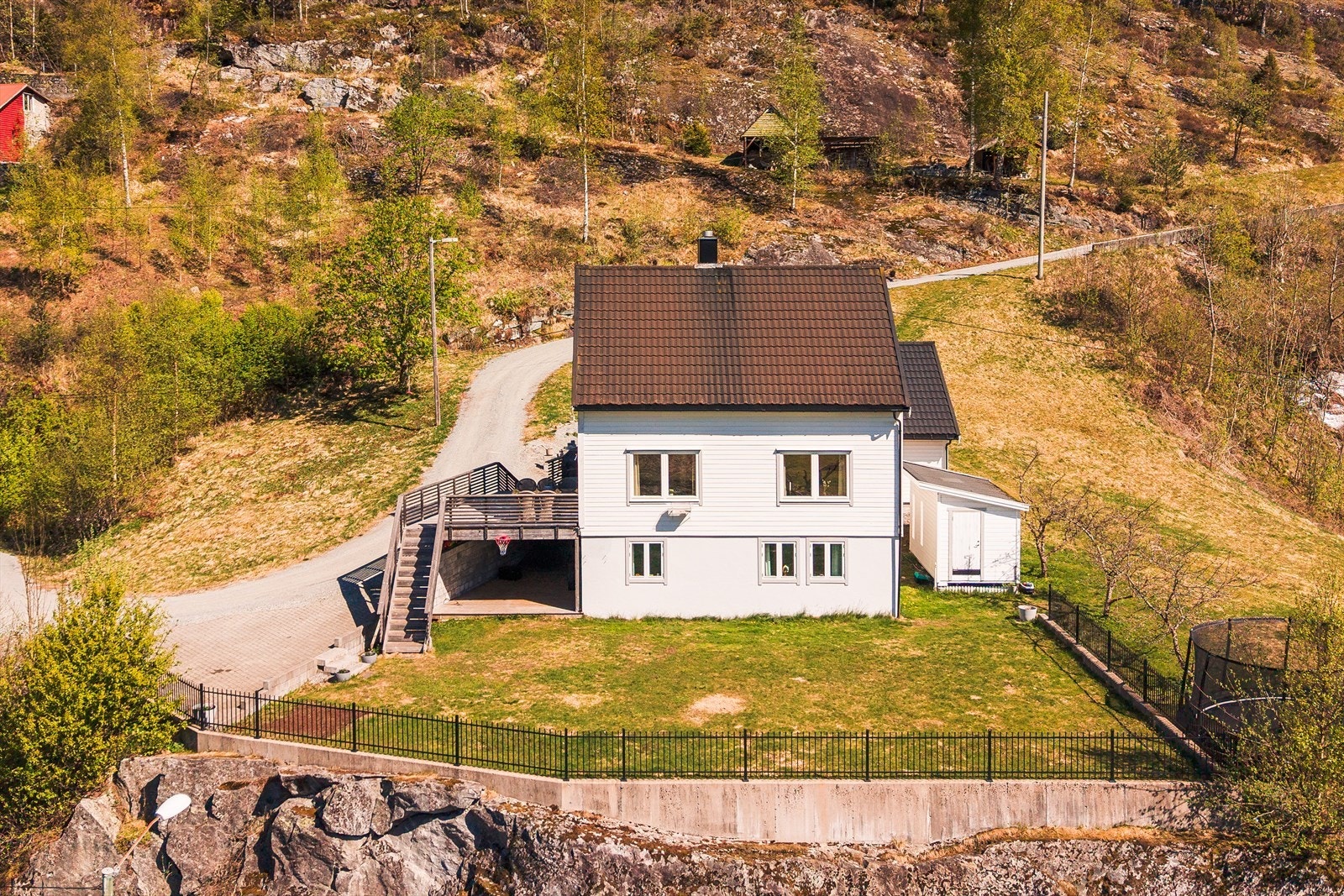 Tomten er pent opparbeidet med plen og kantmurer. Galleribilde