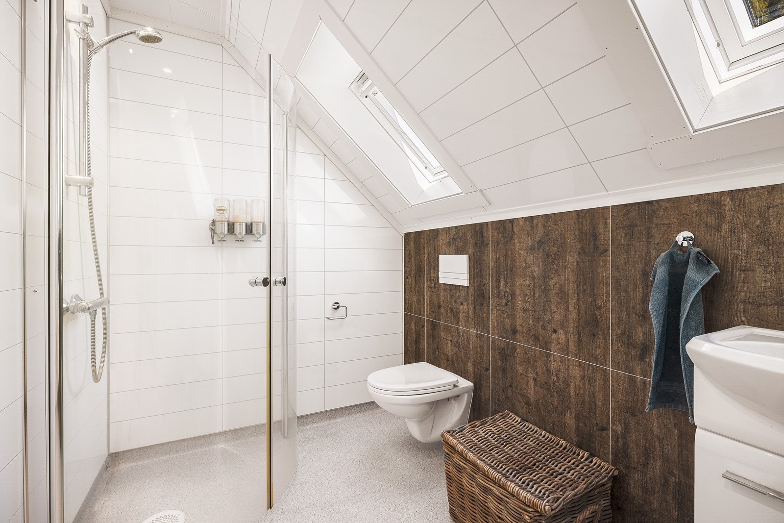 Badet er innredet med vegghengt toalett, dusjhjørne og servant. Takvinduene gir godt med dagslys. Galleribilde