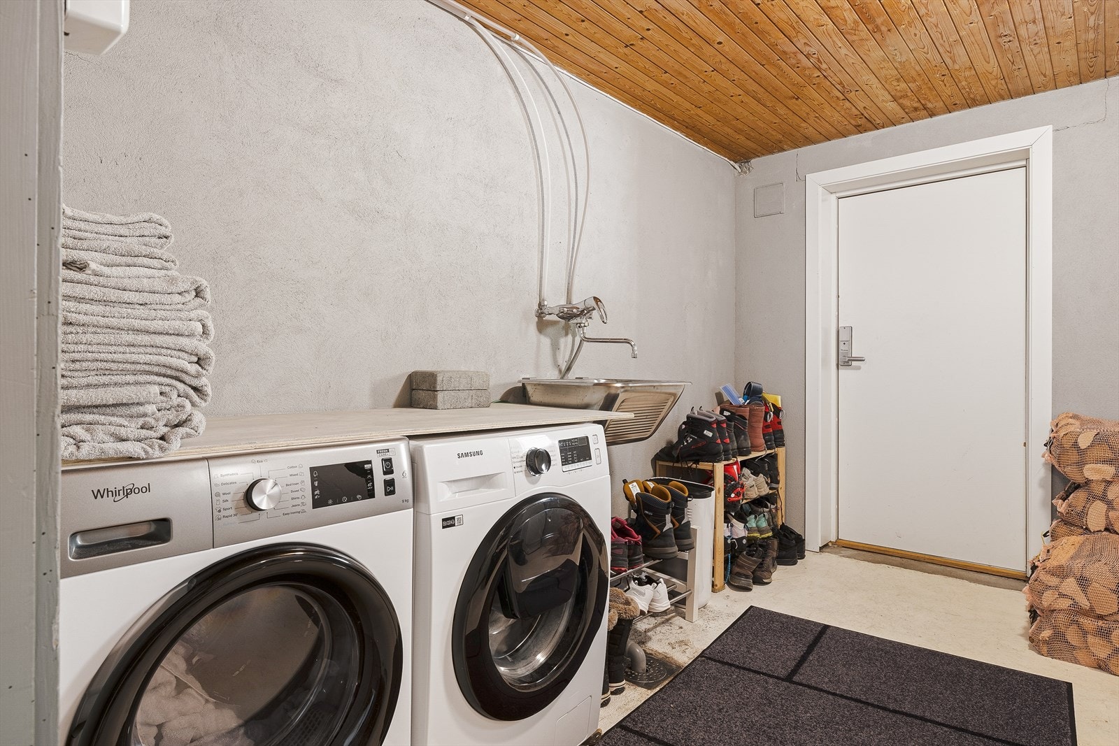 Praktisk vaskerom med betonggulv, opplegg for vaskemaskin og stålvask. Galleribilde