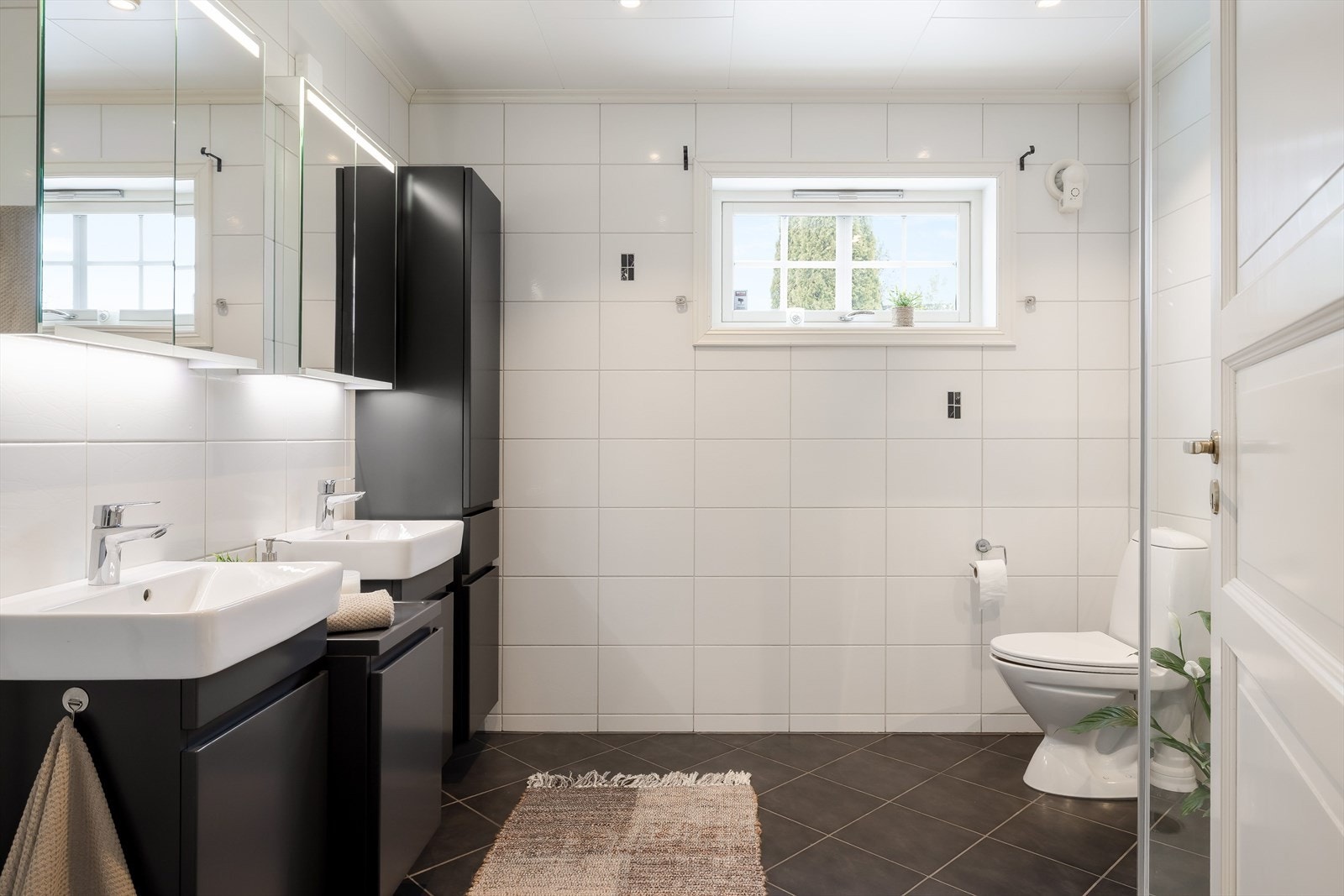 I tilknytning til hovedsoverommet er det et lyst og moderne baderom fra 2007. Baderommet har mørke fliser på gulv, vannbåren gulvvarme, hvite fliser på veggene, downlights i himlingen og mekanisk avtrekk. Galleribilde