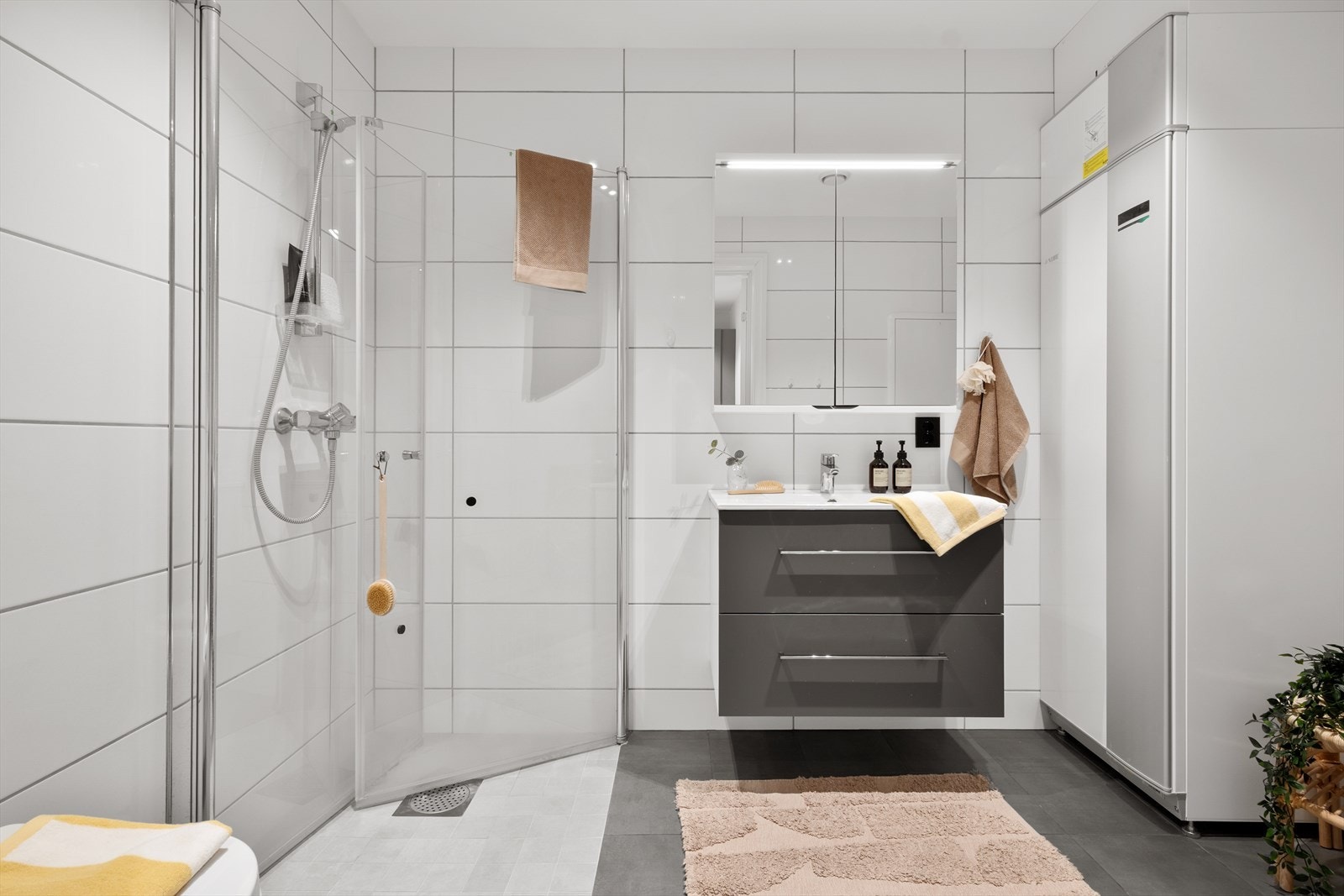 Badet er stort, praktisk og flott med gråe fliser på gulv og litt lysere fliser på vegg. Galleribilde