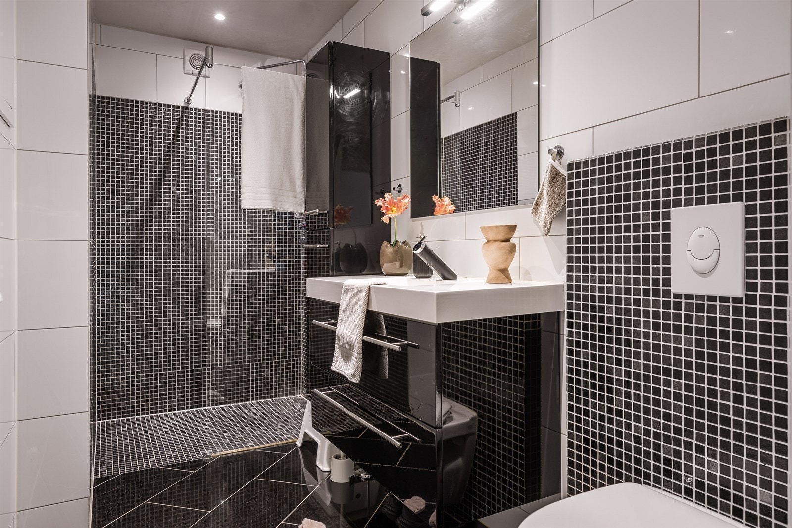 Badet er innredet med veggmontert toalett, servant med innredning og dusjhjørne. Galleribilde