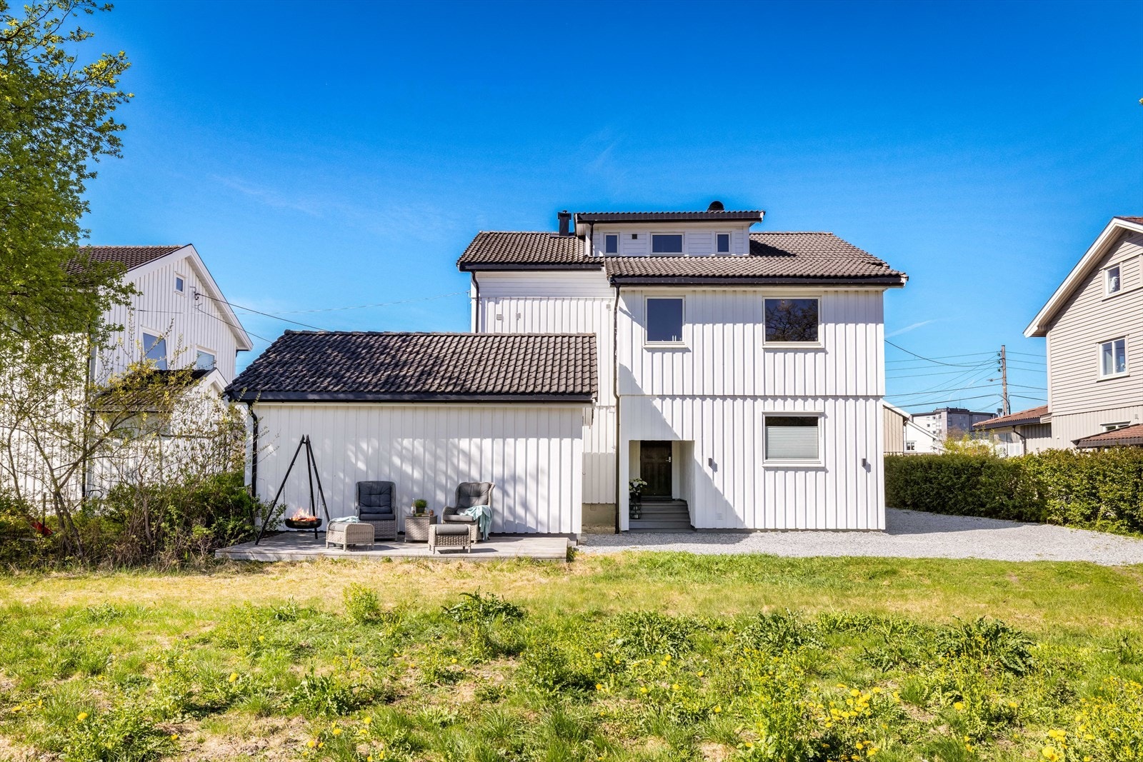 På bakkeplan disponerer denne seksjonen en platting bak garasjen (står delvis på kommunen sin tomt), samt hagedel med gressplen, blomster og drivhus. Galleribilde
