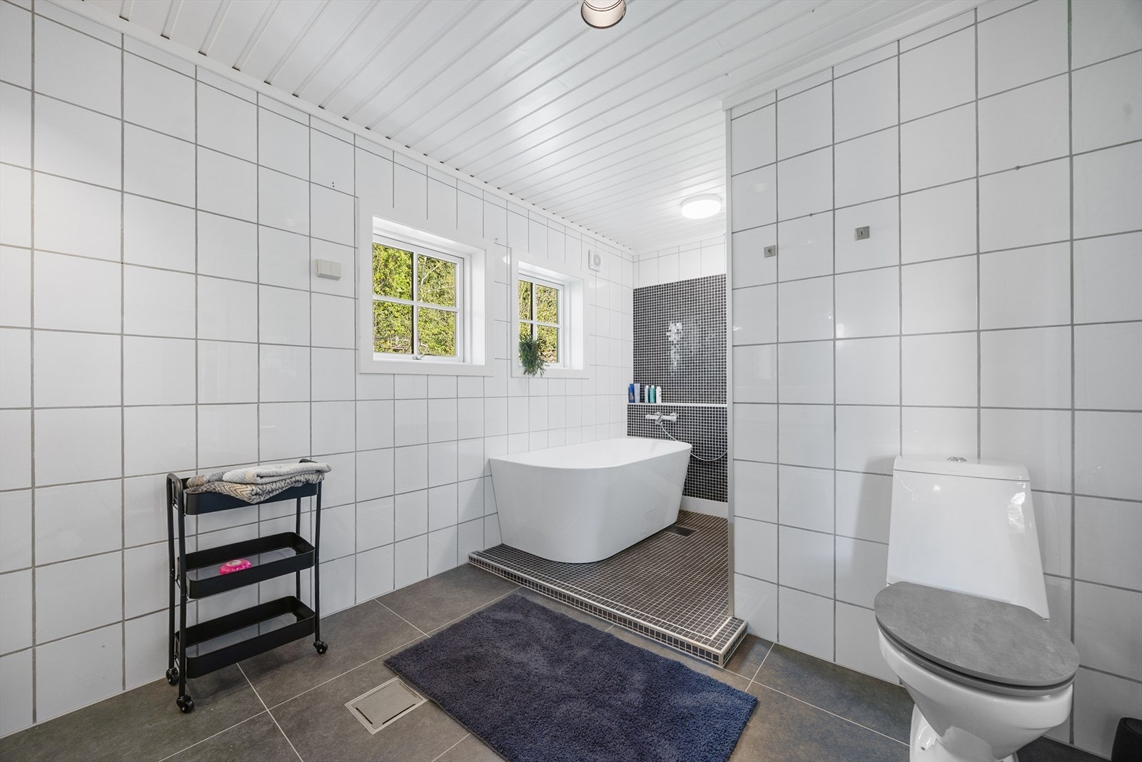 Et romslig og helfliset bad med elektrisk gulvvarme, badekar og dusjnisje. Galleribilde