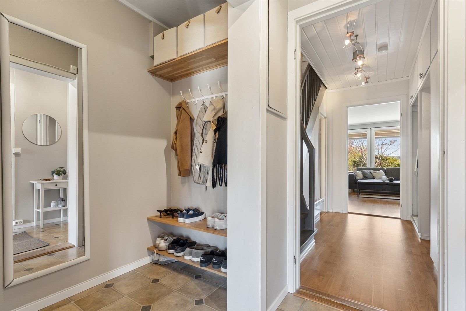 Fra gangen er det en åpen siktlinje mot stuen, og trappeadkomst til de øvrige etasjene. Opprinnelig bod til venstre i bildet er i dag åpnet opp og blitt en del av boligens entré. Galleribilde