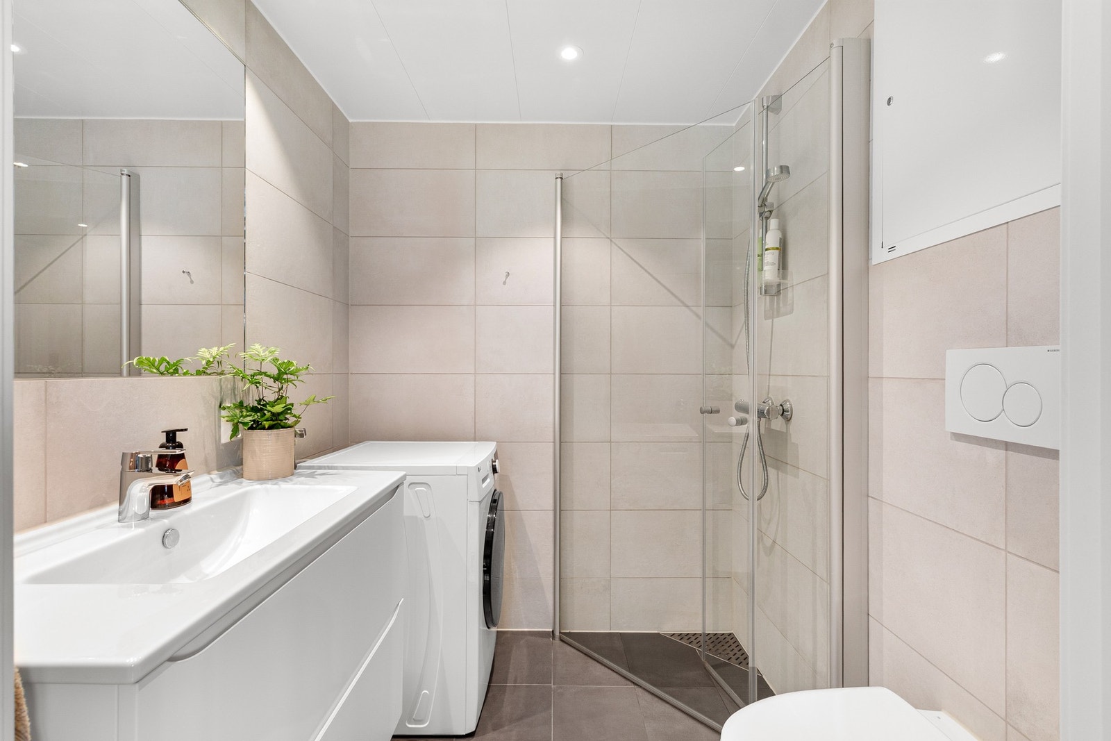 Boligens bad fremstår som moderne med flotte flisvalg. Galleribilde