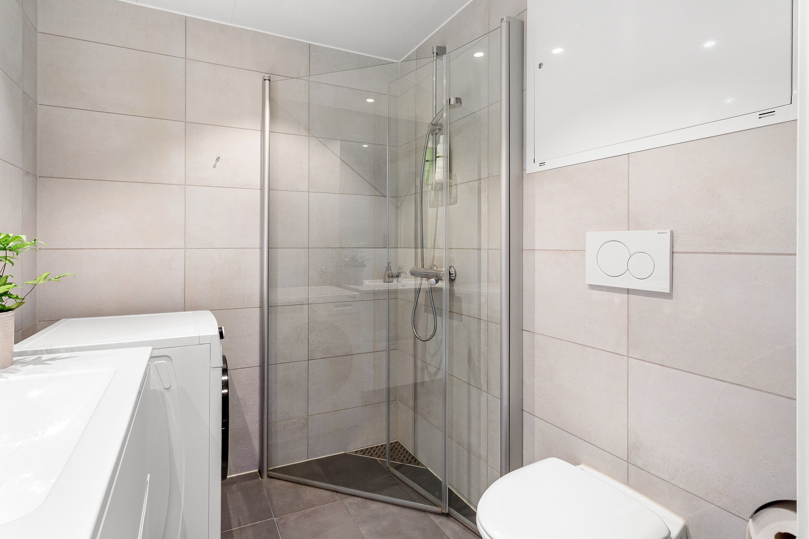 Badet er utstyrt med kran/avløp til vaskemaskin, innfellbare dusjdører i glass, samt grepsfri baderomsinnredning. Galleribilde