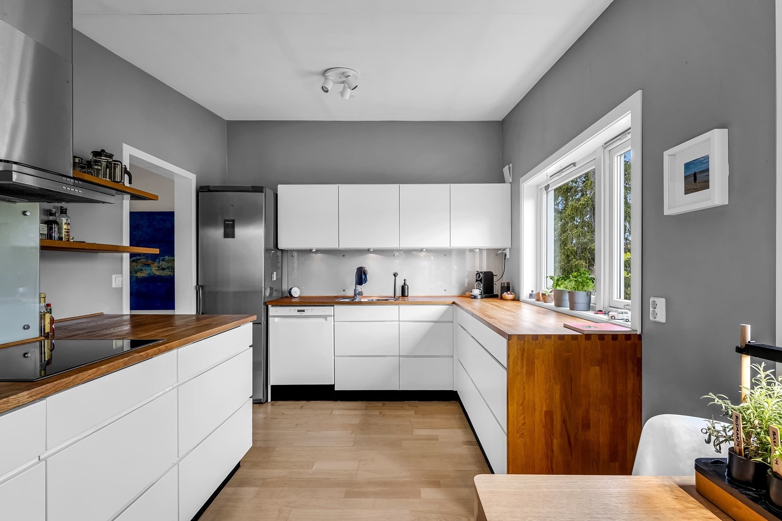 Kjøkken i lyse og moderne utførelser med glatte fronter og benkeplate i heltre. Galleribilde