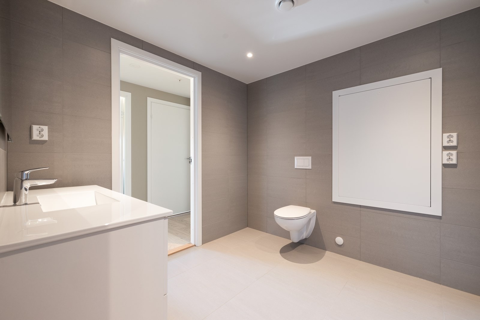 Badet har flis på gulv og vegger. Det er listefri overgang til sparklet og malt gips i tak, med innfelte downlights (LED) med dimmer. Galleribilde