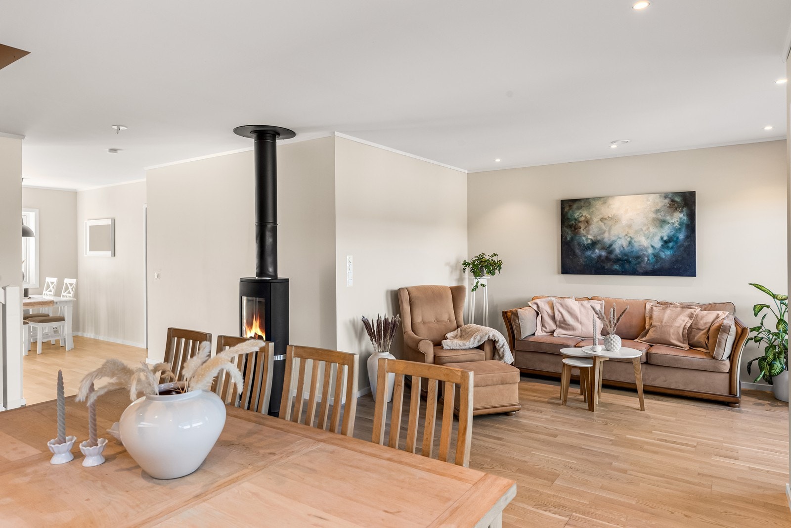 Første etasje har en åpen løsning mellom stue og kjøkken, med en sentralt plassert vedovn som gir både varme og atmosfære. Galleribilde