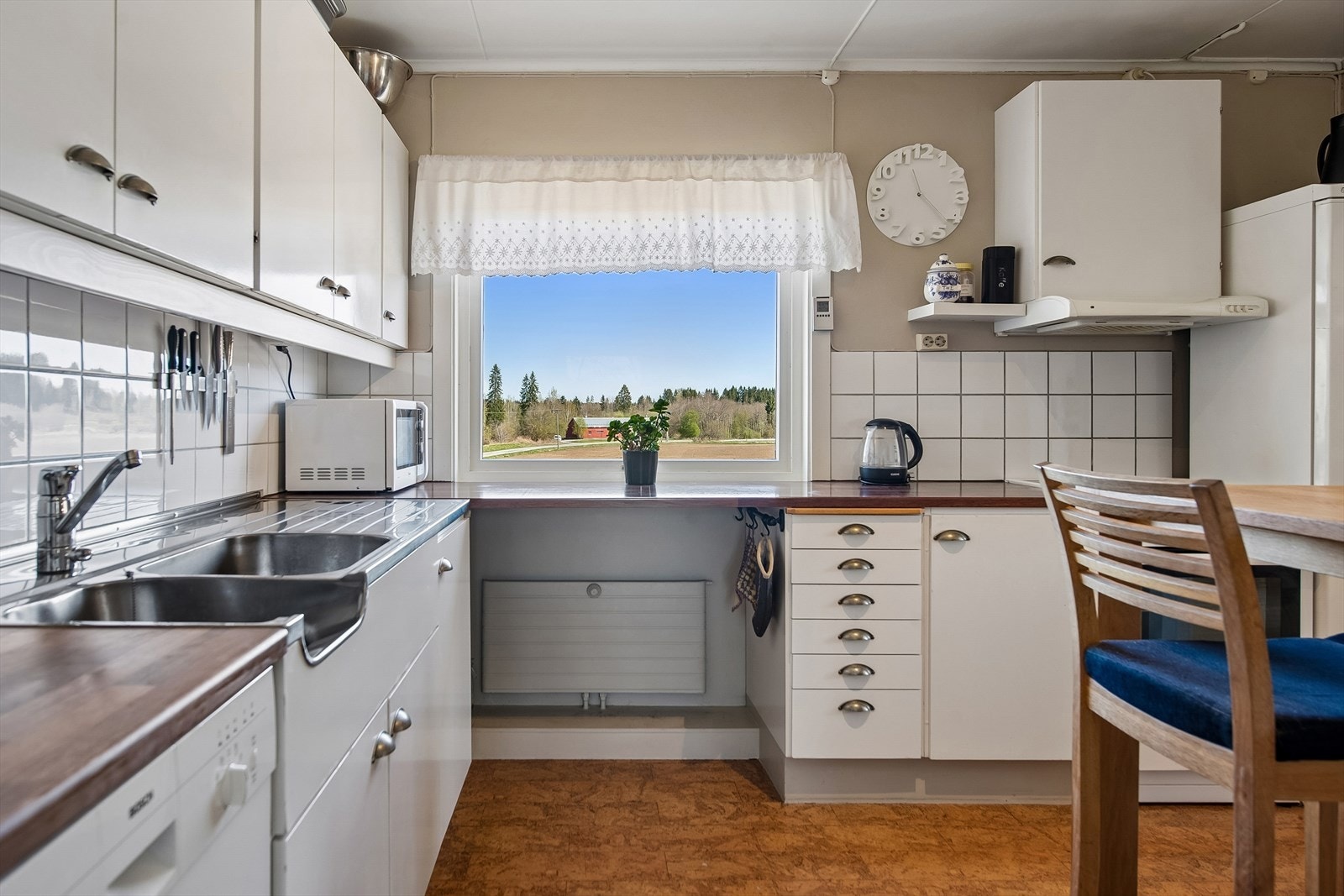 Kjøkkeninnredning med laminert benkeplate og belysning over arbeidsflatene. Det er plass til frittstående hvitevarer. Galleribilde