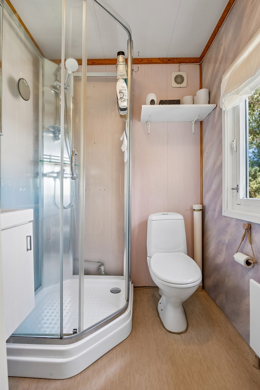 Badet er utstyrt med dusjkabinett, servant med underskap og gulvmontert toalett. Galleribilde