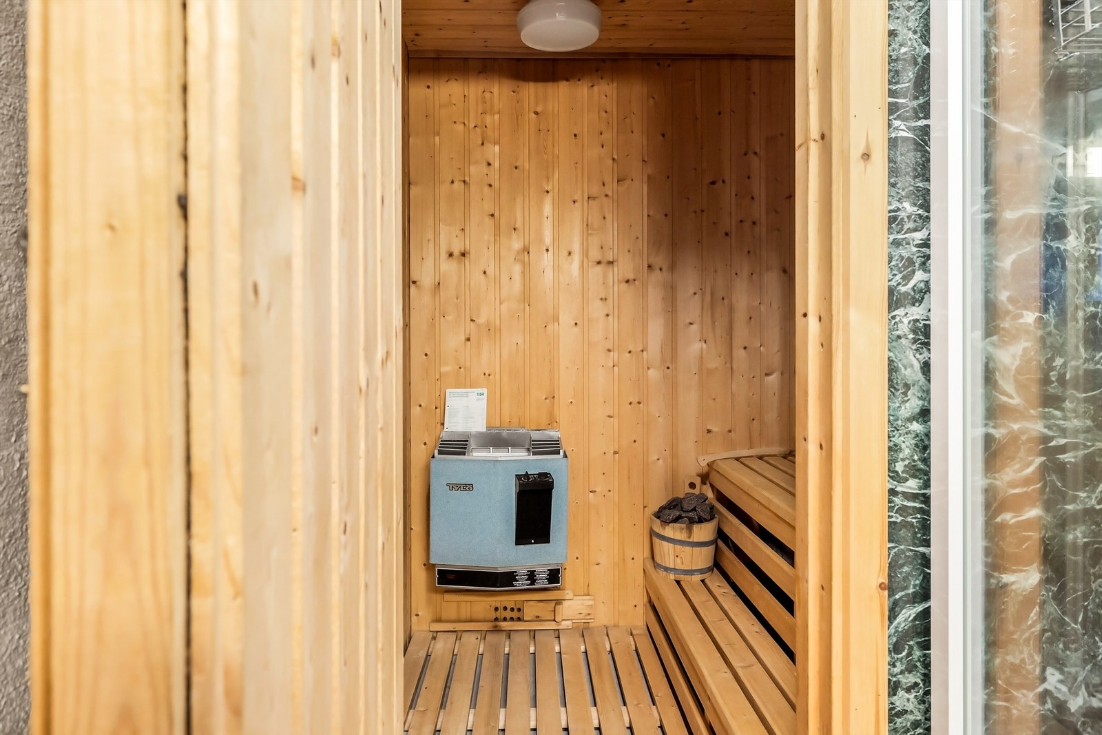 I tilknytning til badet ligger en badstue med panel på vegger, sittebenk og elektrisk ovn. Galleribilde