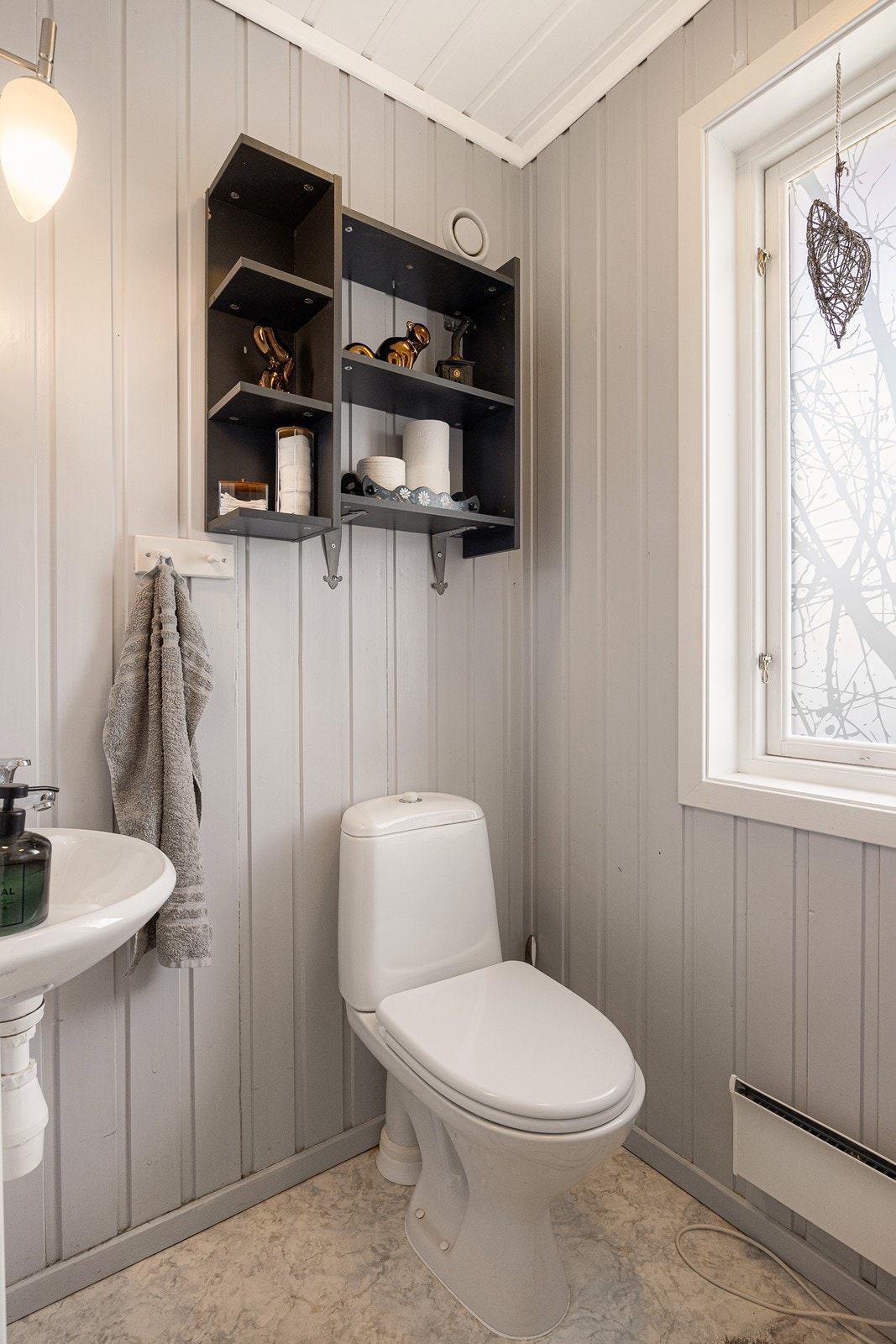 WC-rommet har gråmalt panel på veggene og lyst belegg på gulvet. Galleribilde
