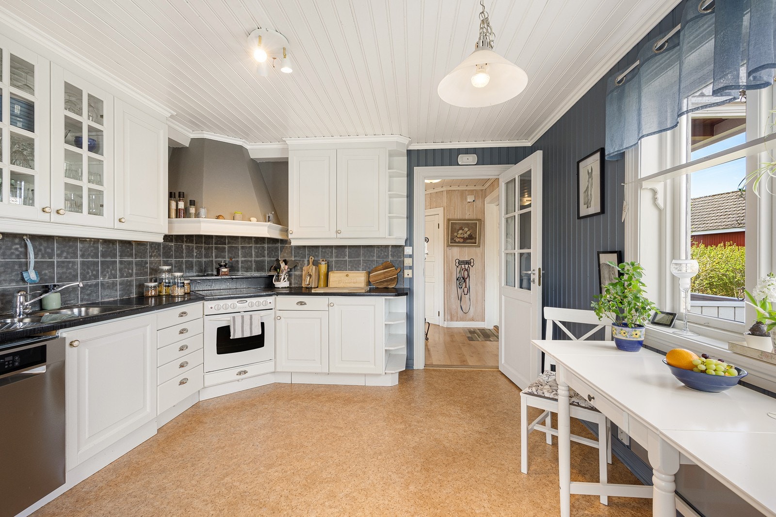 Kjøkkenet har et klassisk og pent design med gode benkeflater og rikelig med oppbevaringsplass. Veggen over benken er kledd med grå fliser, og under overskapene er det montert god arbeidsbelysning. Galleribilde