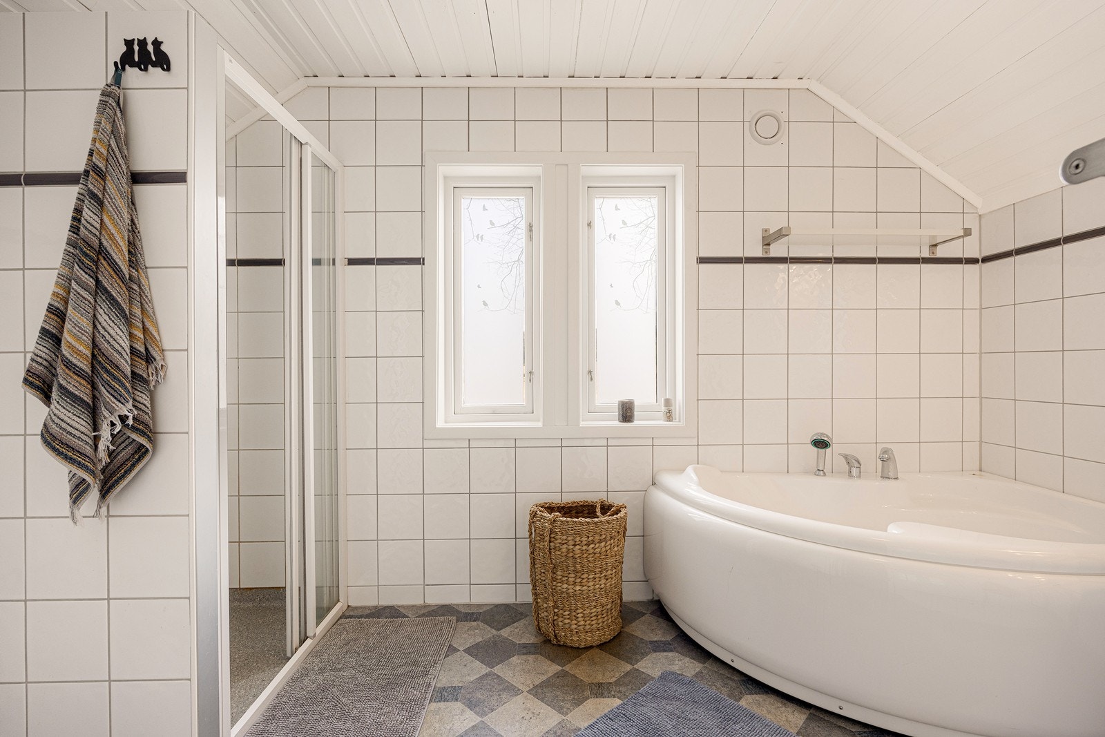 Her er det hvite fliser på veggene, hvitmalt panel i himlingen og grått, mønstret belegg på gulvet. Galleribilde