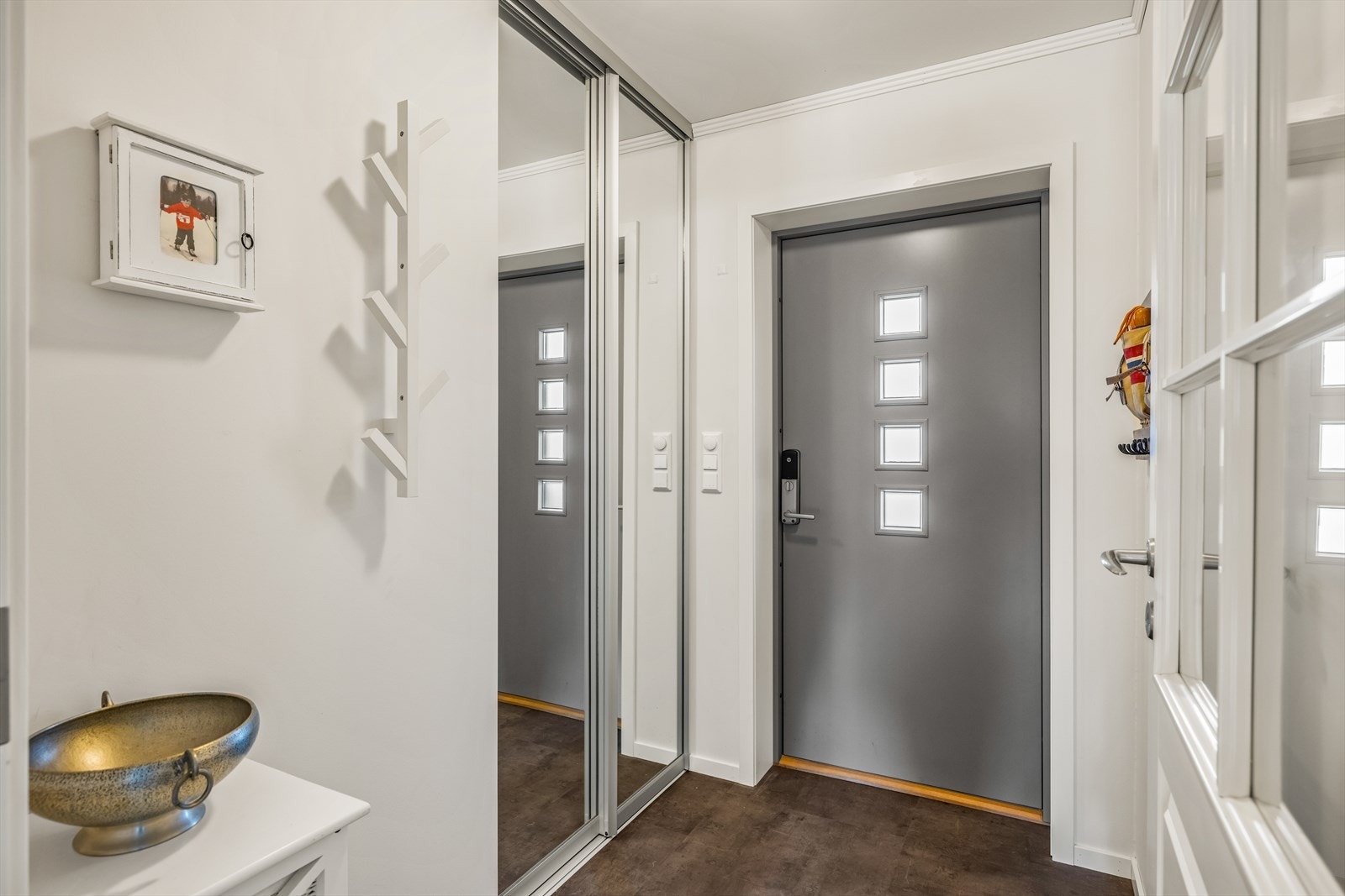 Lys og hyggelig entré gir et fint førsteinntrykk. God plass til lagring i skyvedørsgarderobe og på veggene. Praktisk kodelås på ytterdør. Galleribilde