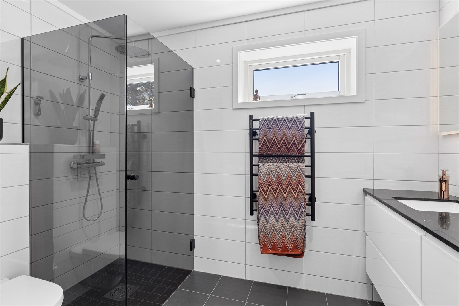 Det private badet som har tilgang fra garderobe, er flislagt og utstyrt med en bred servantinnredning med to nedfelte servanter, vegghengt toalett, dusjvegger og elektrisk håndkletørker. Galleribilde