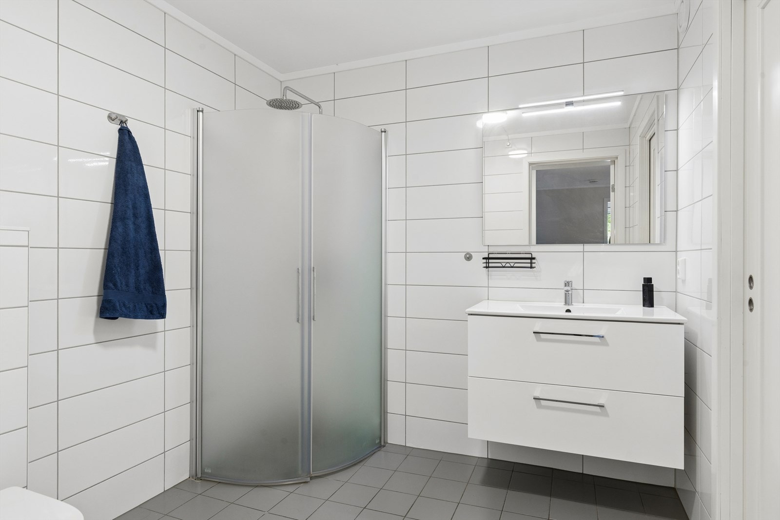 Badet er flislagt og inneholder dusj, servant og vegghengt toalett. Skyvedør inn til bod. Vannbåren varme i gulv. Galleribilde